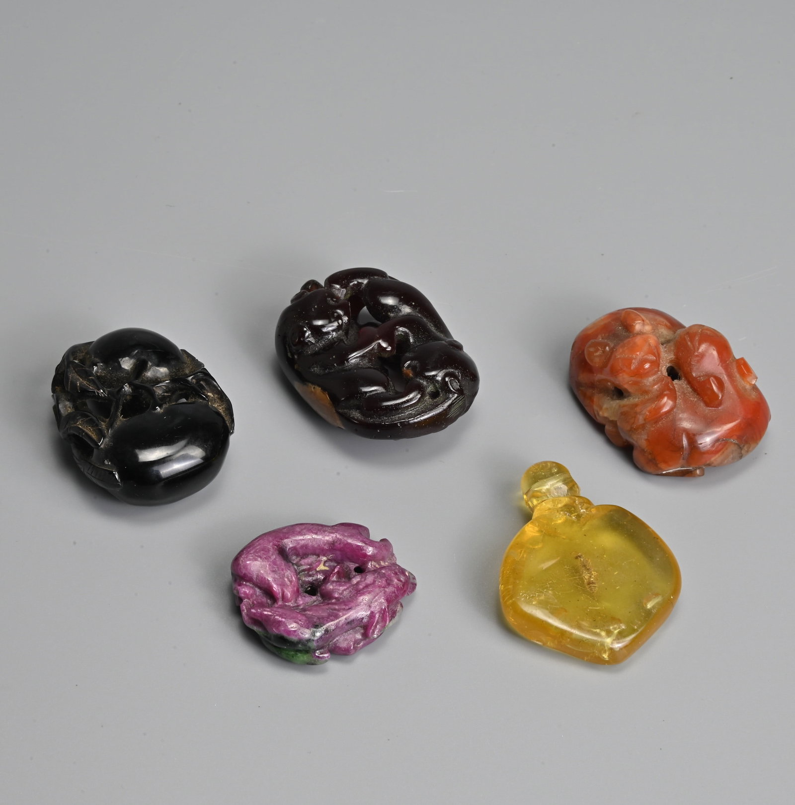 A GROUP OF CHINESE CARVED AMBER, AGATE, RUBY IN ZOISITE PENDANTS, 20TH CENTURY. (1 of 4)