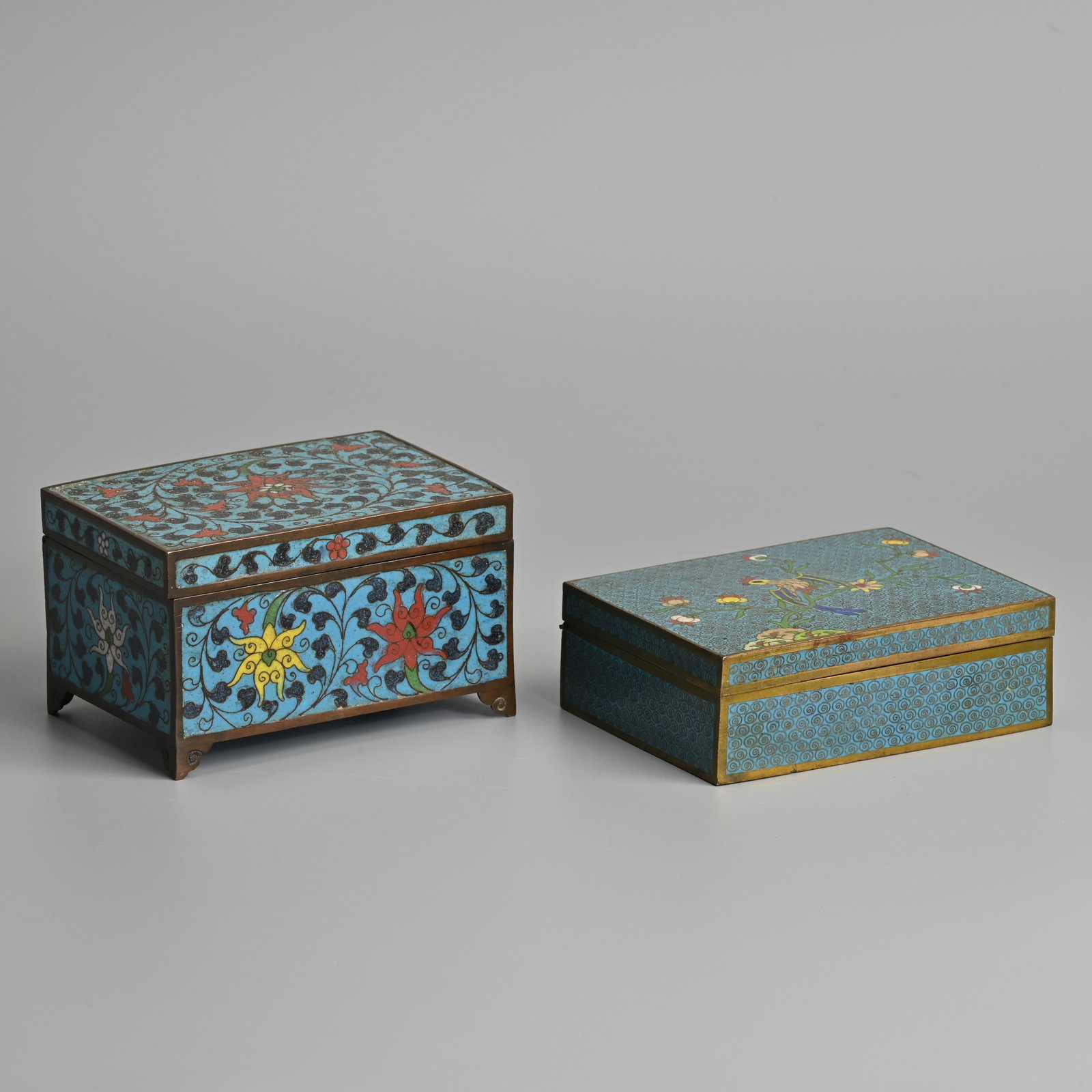 TWO CHINESE CLOISONNE ENAMEL BOXES, 19TH CENTURY.: TWO CHINESE CLOISONNE ENAMEL BOXES, 19TH CENTURY. Of rectangular form with hinged covers, the first decorated with bird perched on a branch with wire cloud scrolls on a light blue ground; Together wit