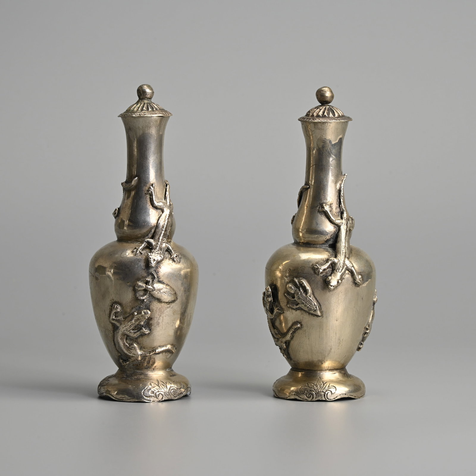 A PAIR OF WHITE METAL VASES WITH COVERS, POSSIBLY MALAY, CIRCA 1900.: A PAIR OF WHITE METAL VASES WITH COVERS, POSSIBLY MALAY, CIRCA 1900. With applied gecko lizards and insects to the body, each with a cover. 14.5cm tall. Gross weight 134 grams. (2).
