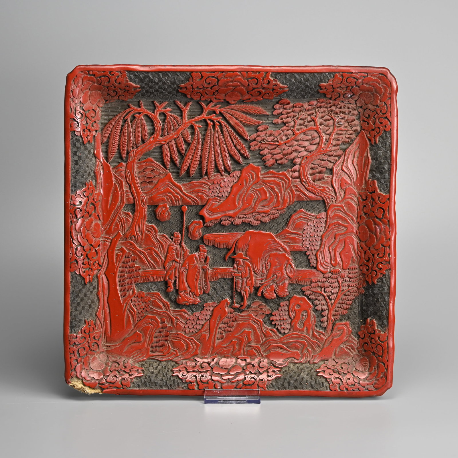 A LARGE CHINESE CARVED CINNABAR LACQUER SQUARE TRAY, 19TH CENTURY, QING DYNASTY.: A LARGE CHINESE CARVED CINNABAR LACQUER SQUARE TRAY, 19TH CENTURY, QING DYNASTY. Featuring a scholar and attendant approaching a man with elephant within a landscape scene of rockwork and trees surrou