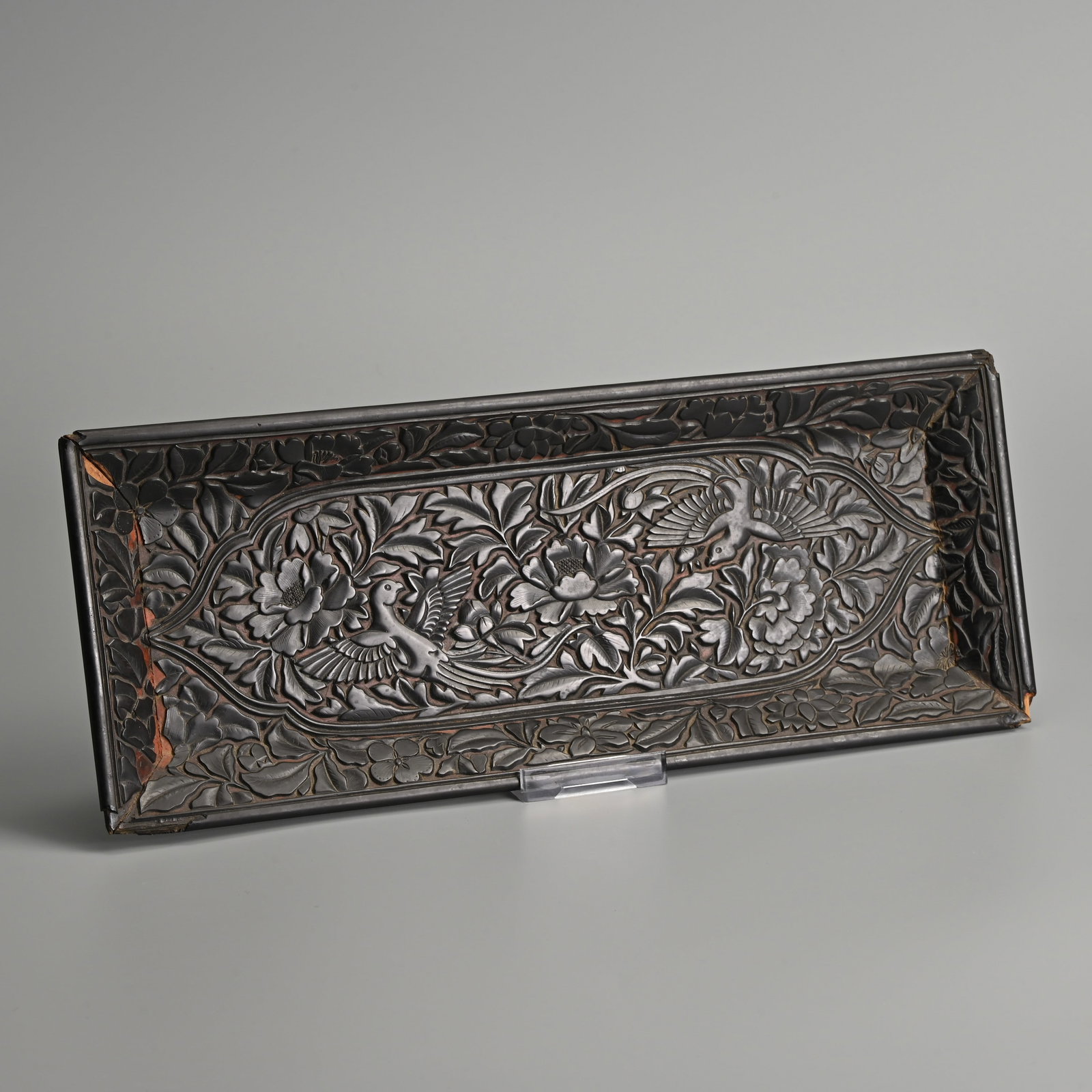 A CHINESE CARVED BLACK LACQUER 'BIRD AND FLORAL' TRAY, MING DYNASTY.: A CHINESE CARVED BLACK LACQUER 'BIRD AND FLORAL' TRAY, MING DYNASTY. Of rectangular form featuring two birds within dense flowers and foliage. The exterior with recessed scroll work. 35.5cm x 14cm.