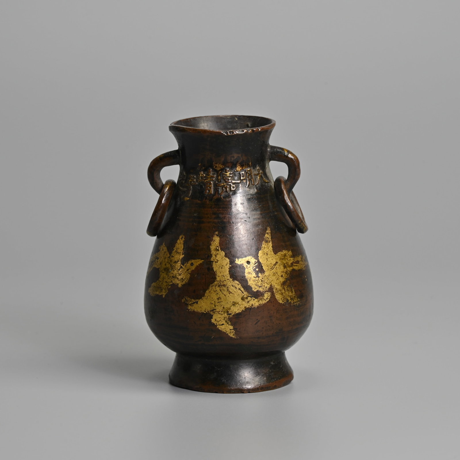 A SMALL CHINESE PARCEL GILT BRONZE 'GEESE' VASE, JIAJING MARK AND OF THE PERIOD.: A SMALL CHINESE PARCEL GILT BRONZE 'GEESE' VASE, JIAJING MARK AND OF THE PERIOD. Pear shaped vase raised on a splayed foot with looped ring handles, decorated with six geese in flight under a crescent