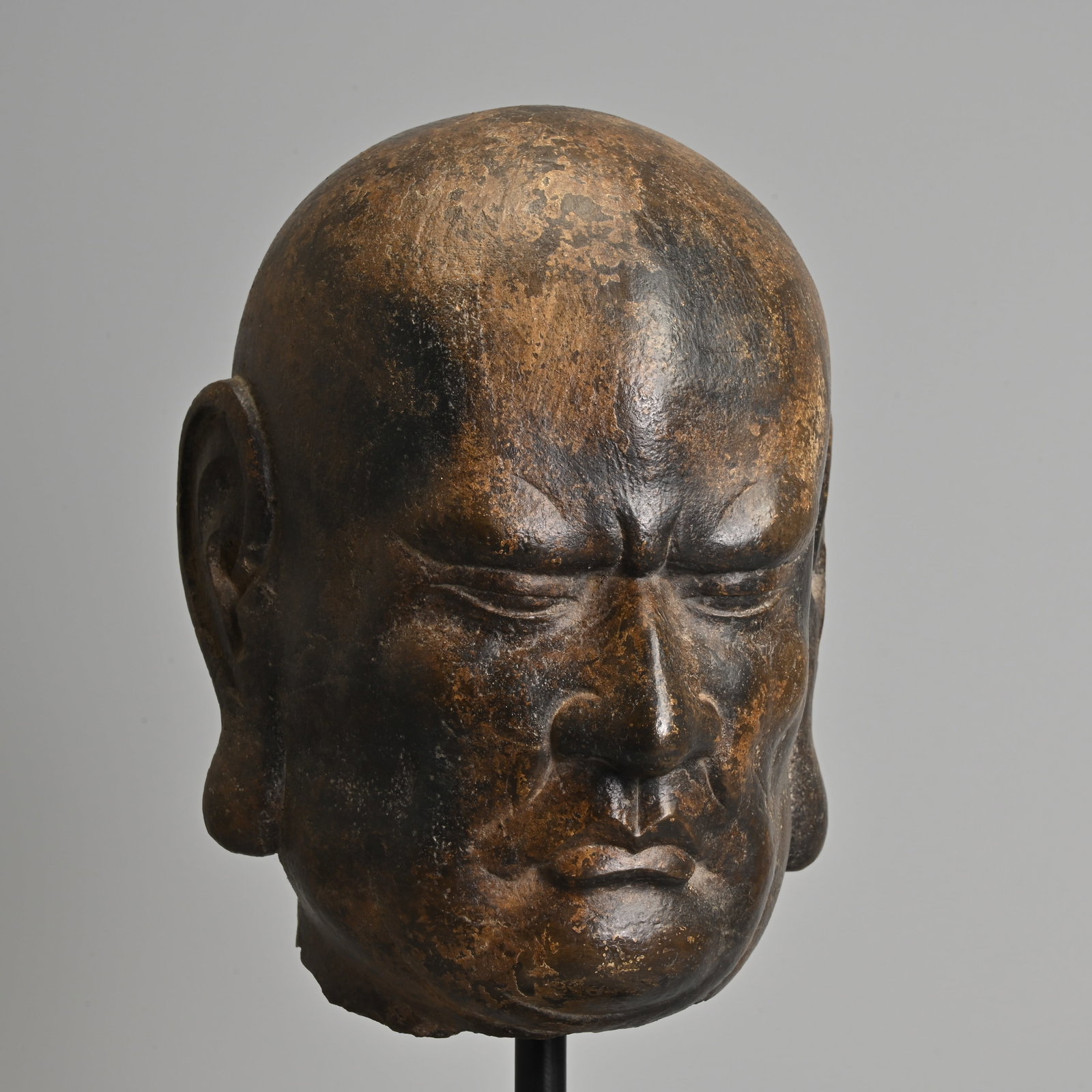 A CHINESE CARVED GREY LIMESTONE HEAD OF LUOHAN, SONG TO MING DYNASTY.: A CHINESE CARVED GREY LIMESTONE HEAD OF LUOHAN, SONG TO MING DYNASTY. Depicted with furrowed brow in deep concentration with a pursed mouth and long pendulous ears. Drilled to the underside and mounte