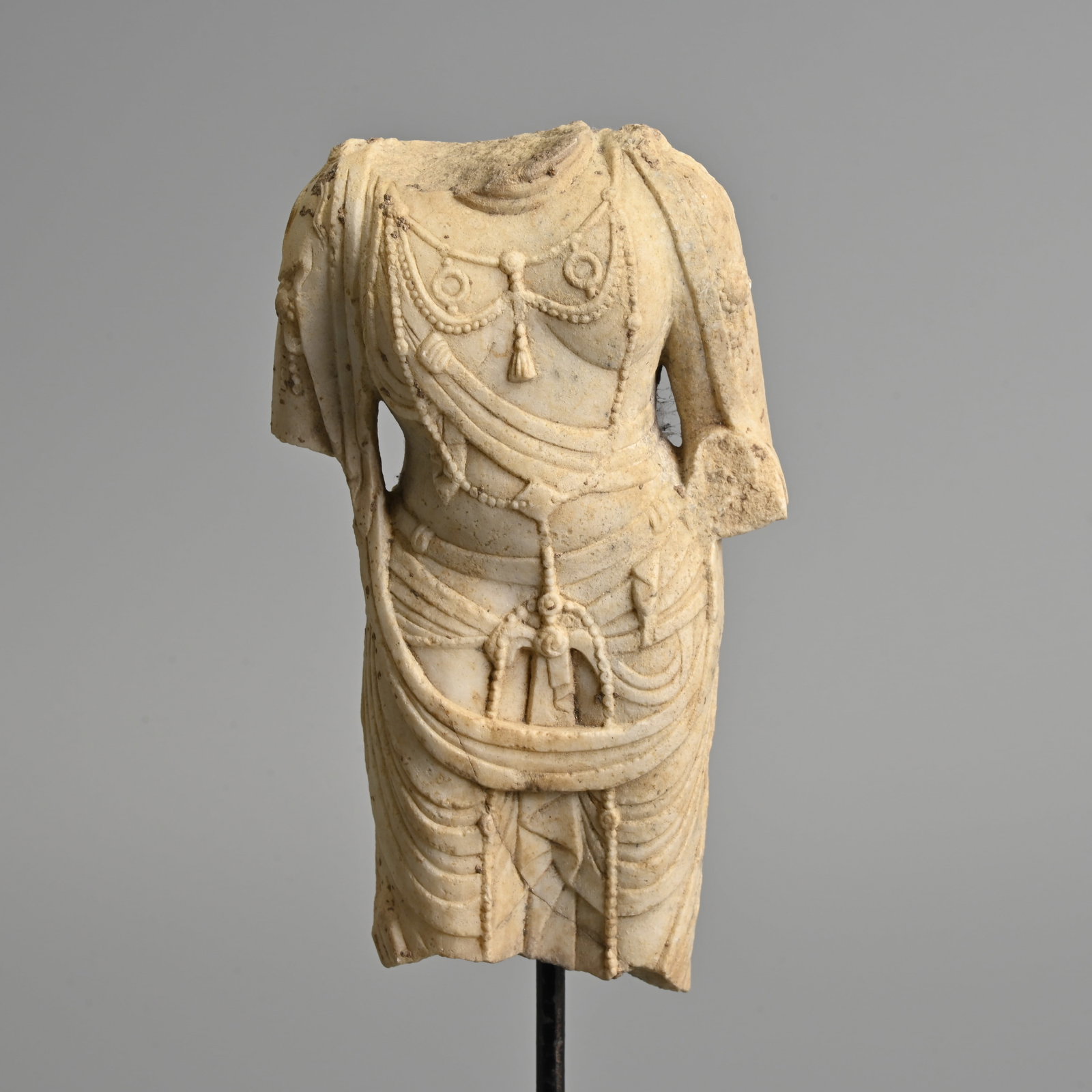 A CHINESE WHITE MARBLE TORSO OF BODHISATTVA, MOUNTED ON STAND.: A CHINESE WHITE MARBLE TORSO OF BODHISATTVA, MOUNTED ON STAND. Carved in the round wearing a dhoti tied at the waist, draping over the shoulders, with a long elaborate beaded necklace with pendants. M