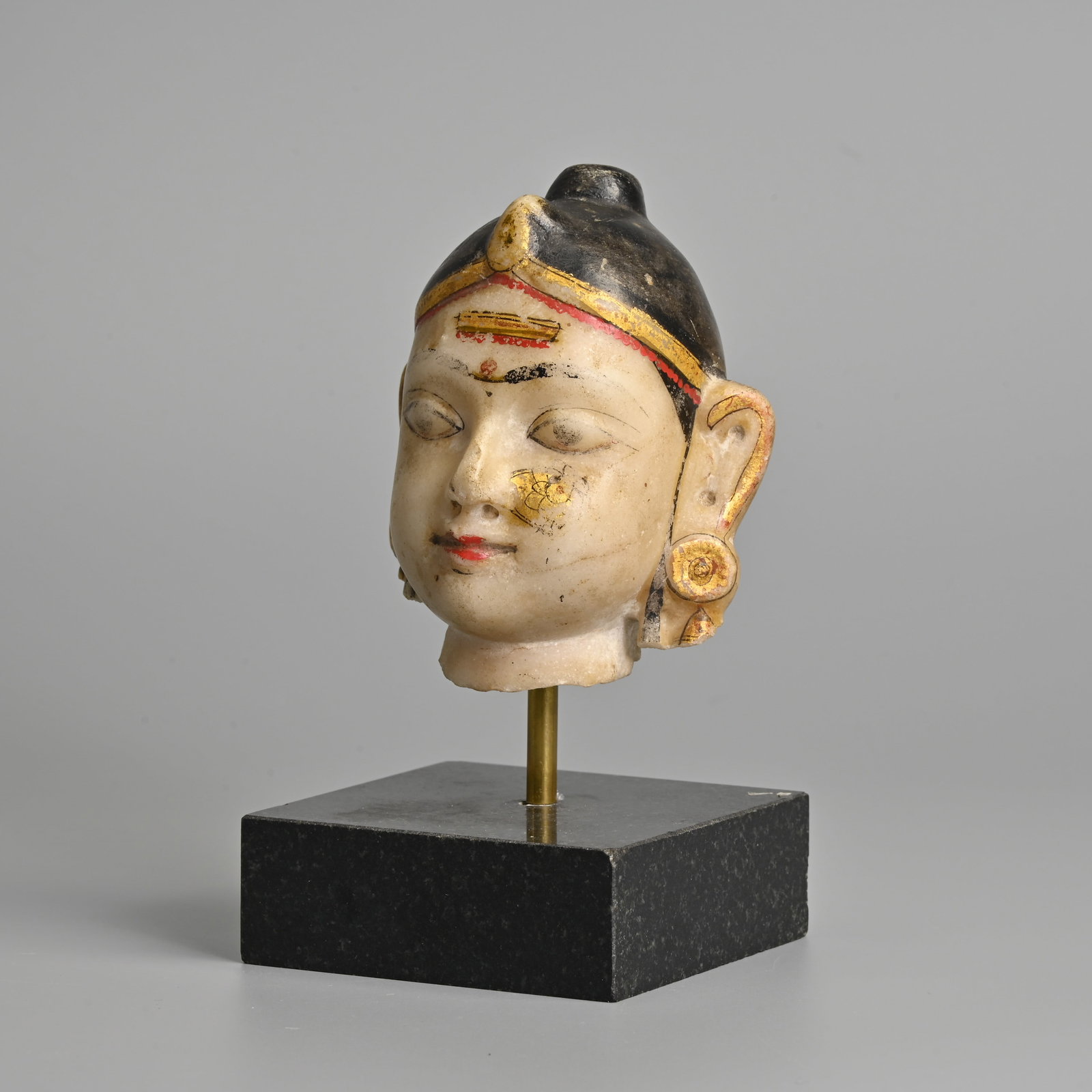 AN INDIAN PAINTED AND GILT DECORATED WHITE MARBLE HEAD OF A DEITY, PROBABLY RAJASTHAN, 19TH CENTURY. (1 of 8)