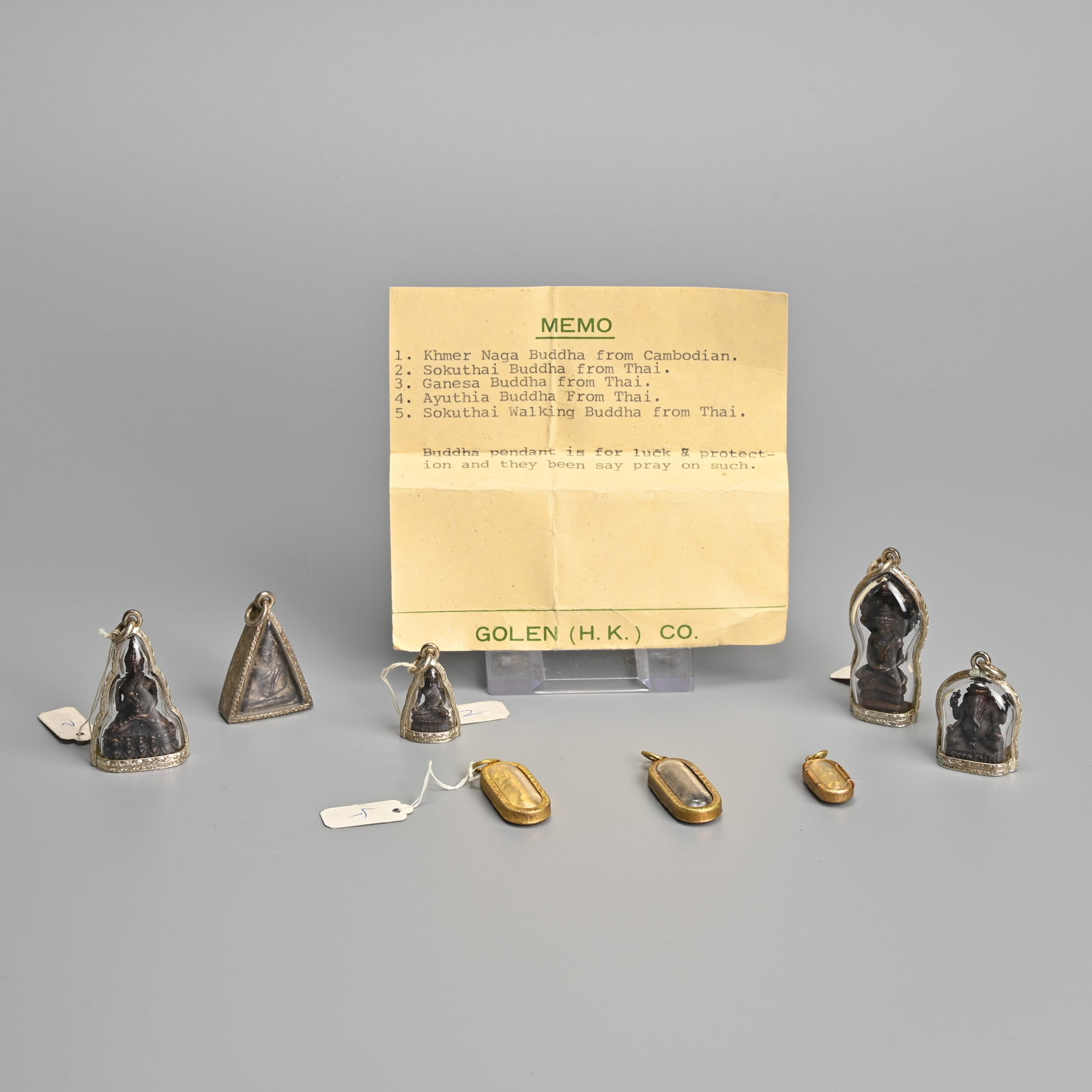 A GROUP OF SOUTHEAST ASIAN BUDDHA AMULET PENDANTS, 20TH CENTURY.: A GROUP OF SOUTHEAST ASIAN BUDDHA AMULET PENDANTS, 20TH CENTURY. Together with a memo card from Golen H.K Co, noting pendants as 1. Khmer Naga Buddha, Cambodia; 2. Sokuthai Buddha, Thailand; 3. Ganesa