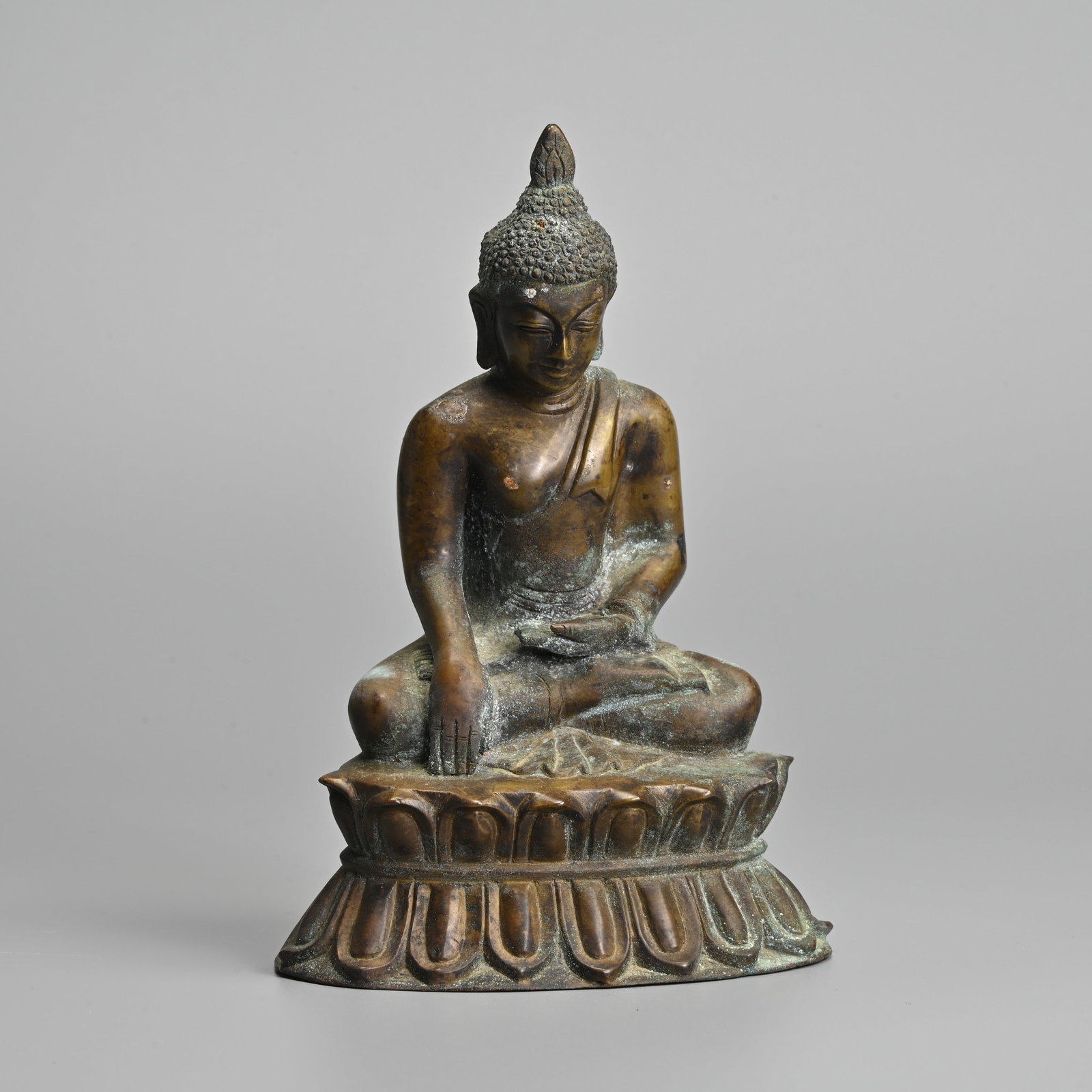 A HIMALAYAN BRONZE FIGURE OF BUDDHA SHAKYAMUNI, EARLY 20TH CENTURY.: A HIMALAYAN BRONZE FIGURE OF BUDDHA SHAKYAMUNI, EARLY 20TH CENTURY. Seated in bhumisparsha mudra on a lotus base dressed in robe. 18.5cm tall.