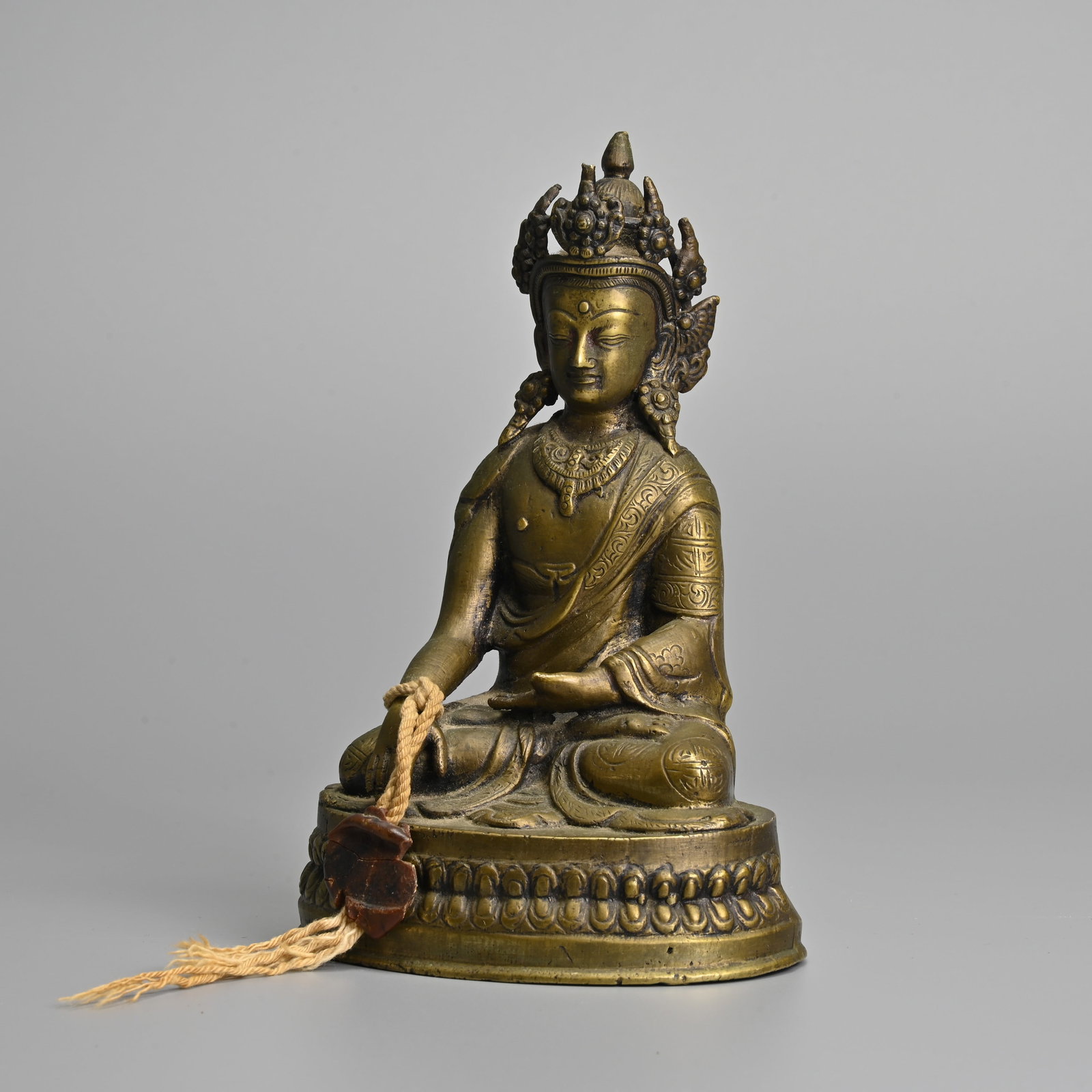 A SINO TIBETAN BRONZE FIGURE OF SHAKYAMUNI, EARLY 20TH CENTURY.: A SINO TIBETAN BRONZE FIGURE OF SHAKYAMUNI, EARLY 20TH CENTURY. Seated in dhyanasana on a lotus base dressed in robes with jewelled necklaces and headdress. 17cm tall.