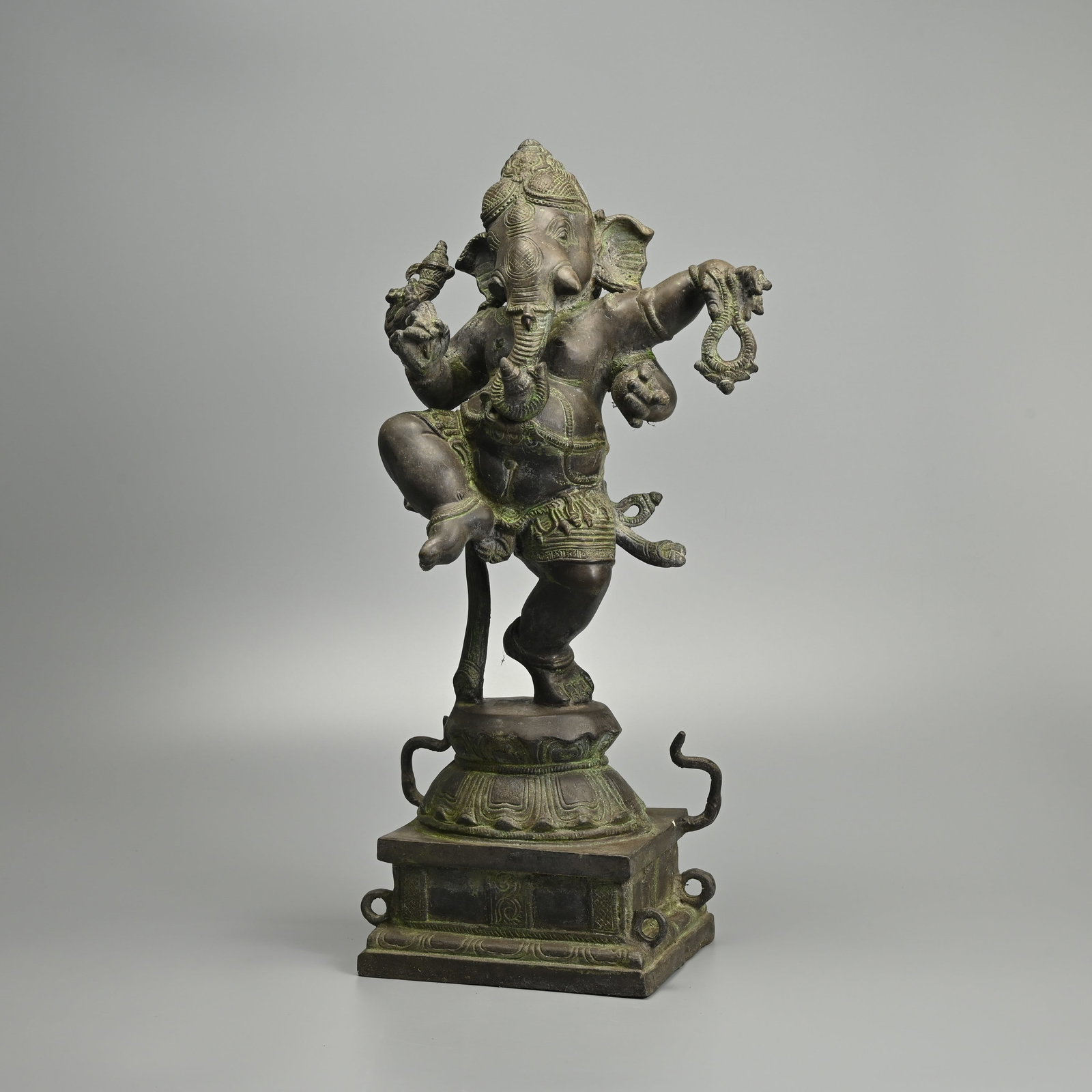 A LARGE INDIAN BRONZE FIGURE OF GANESHA, EARLY 20TH CENTURY.: A LARGE INDIAN BRONZE FIGURE OF GANESHA, EARLY 20TH CENTURY. Standing with one leg raised on a waisted double lotus base over a plinth, holding various attributes in his hands and trunk. 51cm tall. Pr