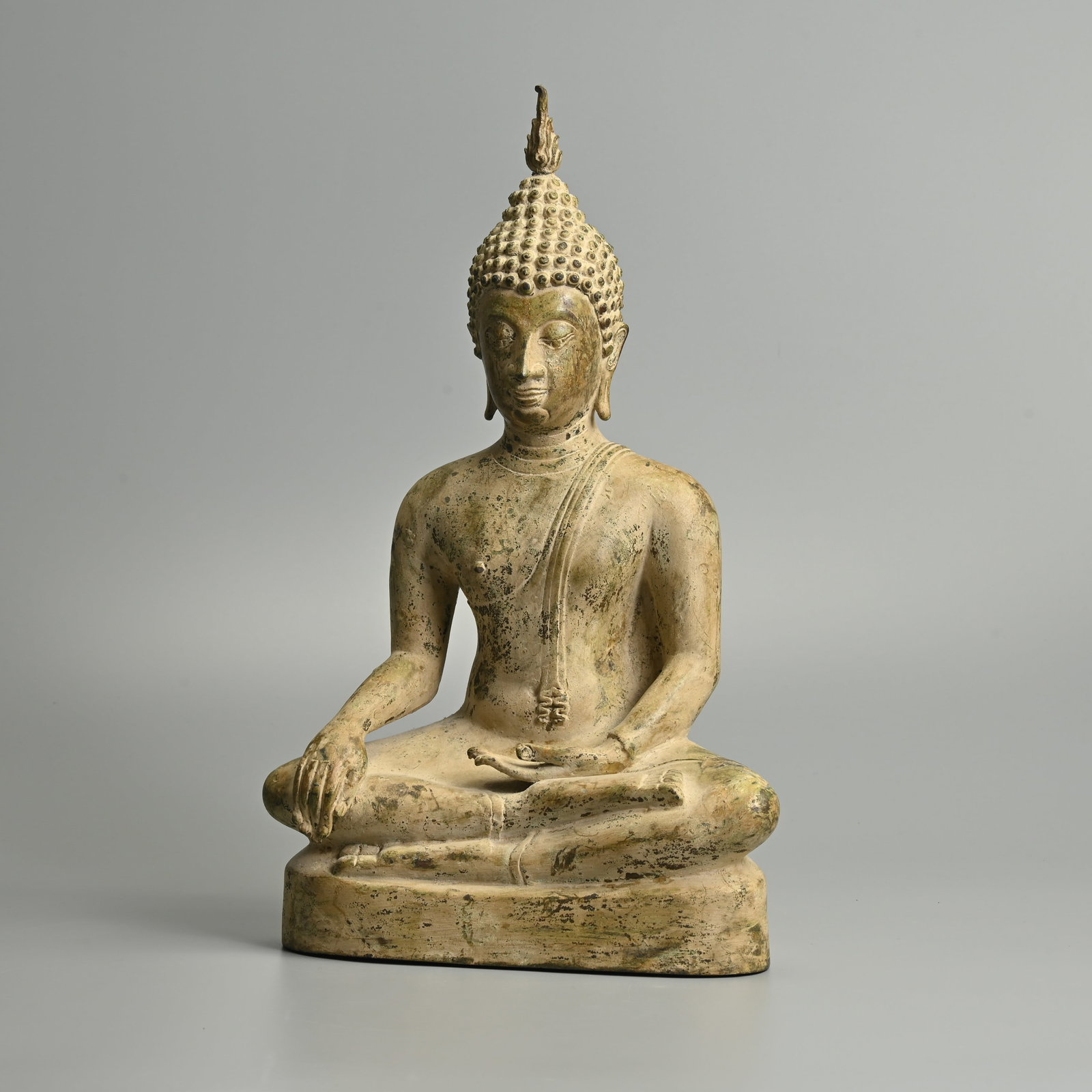 A THAI SEATED BRONZE BUDDHA, 20TH CENTURY.: A THAI SEATED BRONZE BUDDHA, 20TH CENTURY. Seated wearing a samghati, with his right hand in bhumisparshamudra and his left resting on his lap. The head surmounted by a flame. 36cm tall.