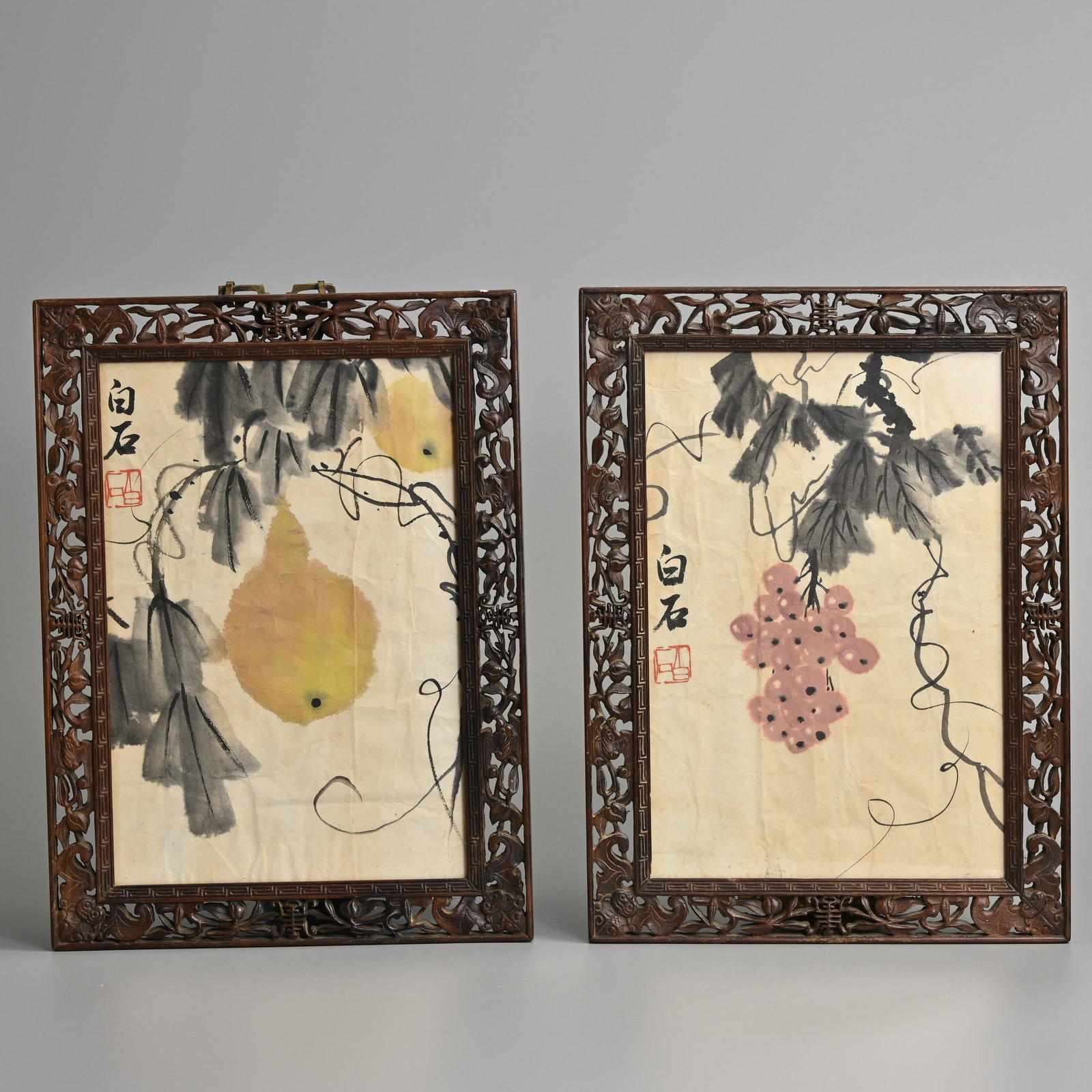 ATTRIBUTED TO QI BAISHI (1863-1957), FRAMED INK AND COLOUR PAINTINGS ON PAPER.: ATTRIBUTED TO QI BAISHI (1863-1957), FRAMED INK AND COLOUR PAINTINGS ON PAPER. Featuring yellow gourds and grapes on vines, each signed Baishi with red seals. Each mounted in carved and pierced wood f