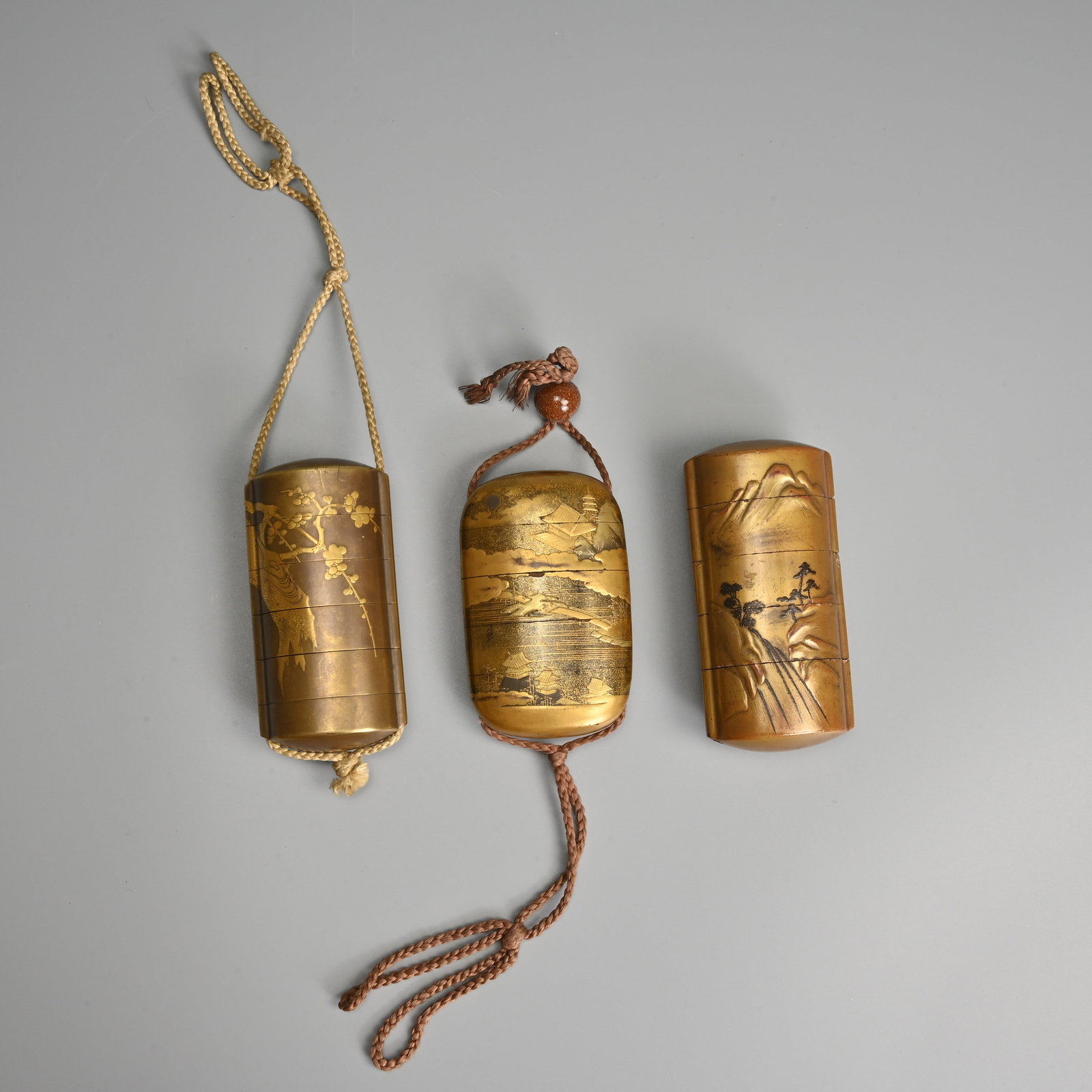 THREE JAPANESE LACQUER INRO, UNSIGNED, MEIJI PERIOD.: THREE JAPANESE LACQUER INRO, UNSIGNED, MEIJI PERIOD. Four and five tiered inro decorated with cherry blossom, and landscape scenes. 9cm - 10cm tall. (3).