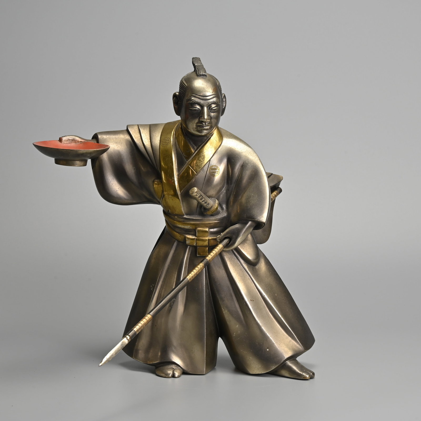 A JAPANESE SILVERED AND PARCEL GILT BRONZE FIGURE OF SAMURAI MORI TAHEI, 20TH CENTURY.: A JAPANESE SILVERED AND PARCEL GILT BRONZE FIGURE OF SAMURAI MORI TAHEI, 20TH CENTURY. The famous samurai is depicted standing with wide stance, clasping his spear in one hand and a large sake cup in 