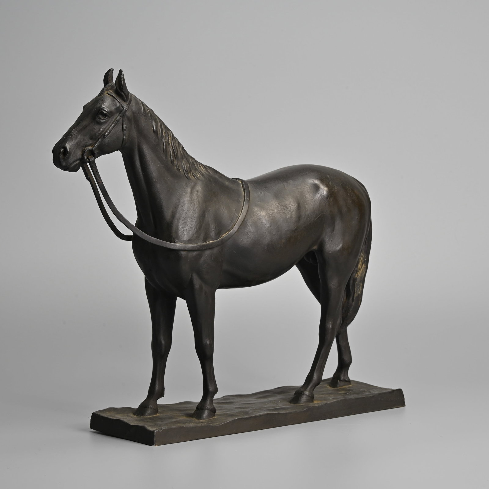 A JAPANESE BRONZE MODEL OF A HORSE, ATTRIBUTED TO KUNIO ITO (1890?1970).: A JAPANESE BRONZE MODEL OF A HORSE, ATTRIBUTED TO KUNIO ITO (1890?1970). Standing foursquare on a rectangular shallow rocky base. Signed to the base. 34cm length x 32cm tall x 9cm deep, weight 5.3kg. 