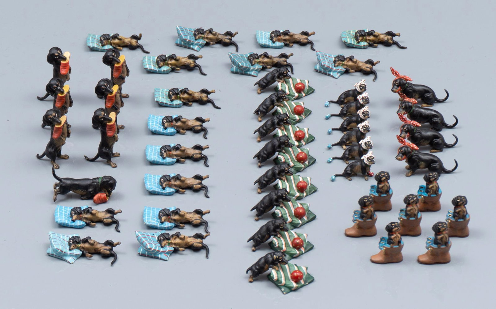 Franz Bergman (1861-1936), 47 Dachshund Figurines: 47 assorted Austrian cold painted bronze dachshund figurines Includes: (10) Dog on blue pillow, (5) Dog on stacked pillows, (8) Dog with ball on pillows, (7) Dog with shoe in mouth, (7) Dog in boot, (