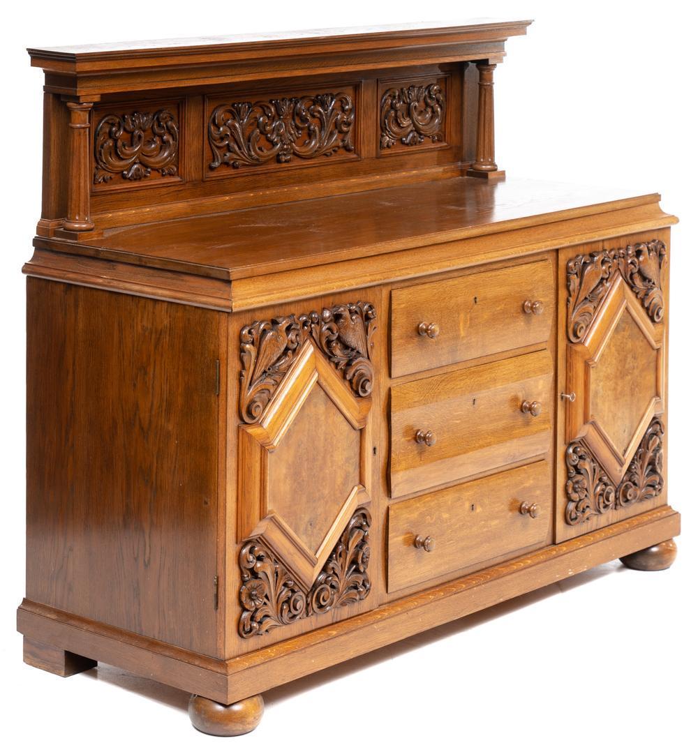 Sideboard: Sideboard cabinet, carved ivy motif, two doors open to shelved interior flanking three drawers, wooden drawer pulls, includes key, rising on bun feet Note: Matching linen press and buffet available in