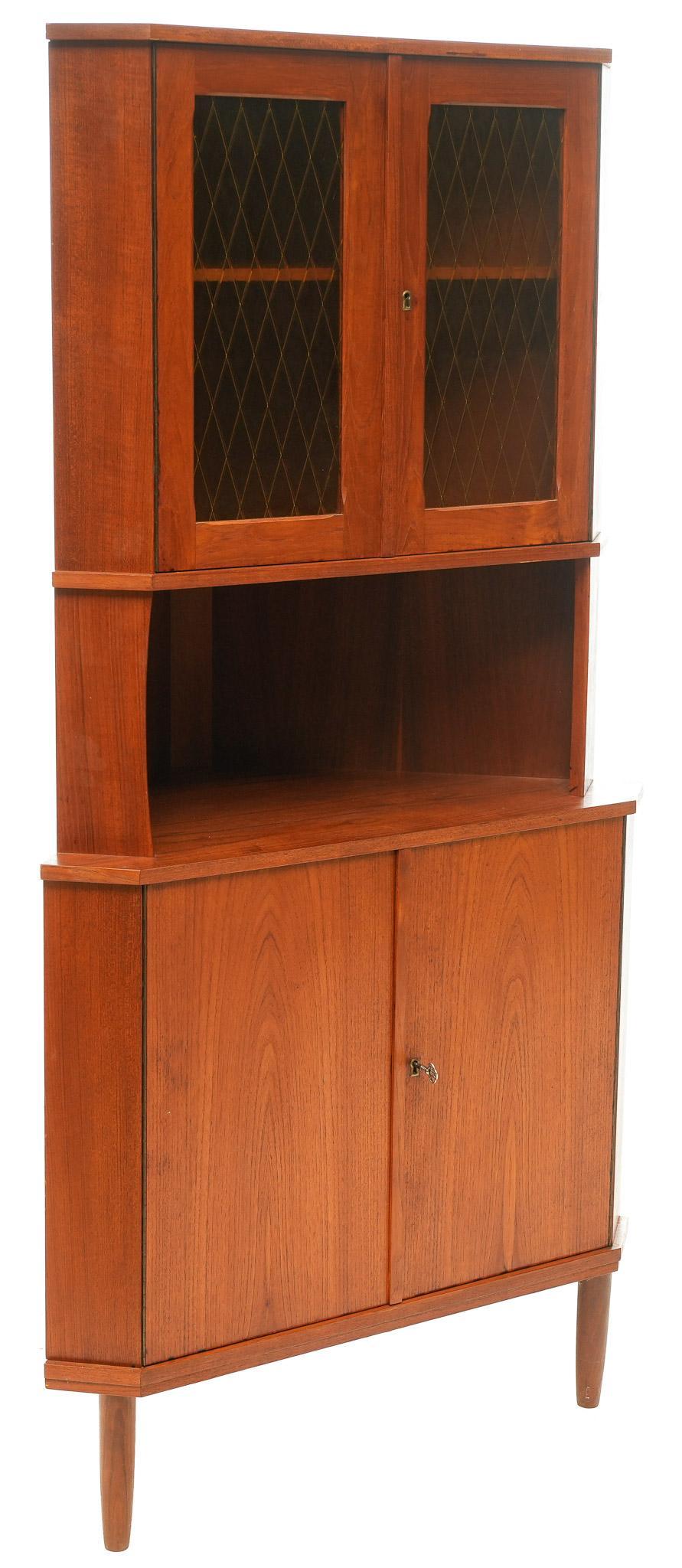 Mid-Century Stained Glass Corner Cabinet: Mid-Century corner cabinet, having two stained glass doors open to shelved interior, above open shelf, above two doors, includes key, rising on pin legs 67.5"h x 34.5"w x 22"d We happily provide sea