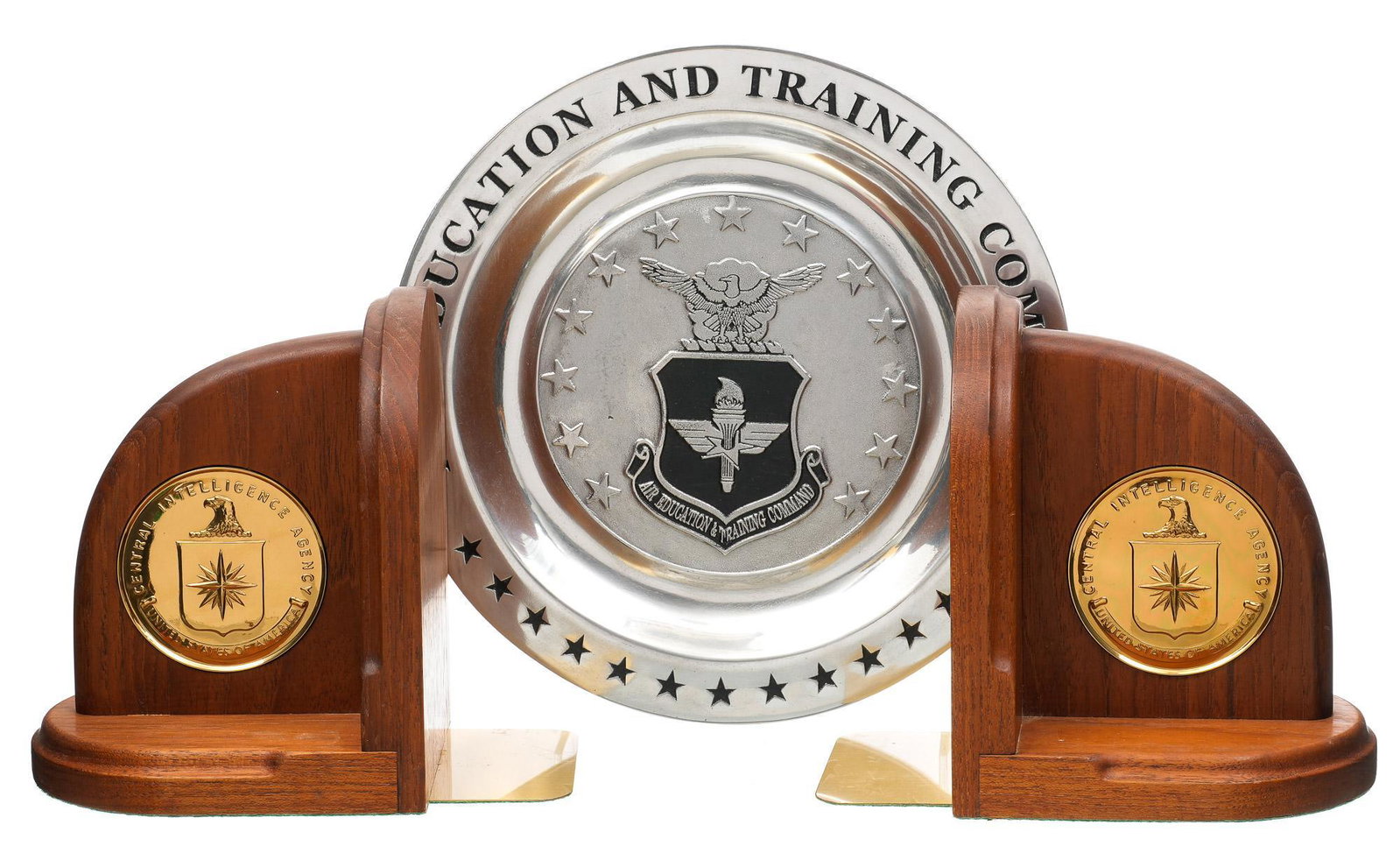 Pair of CIA Bookends & Commemorative Pewter Plate: Includes: -pair of wood bookends w/ brass CIA medallions set into wood; 7 x 7.75 x 5.25" each -pewter Air Education and Training Command commemorative plate; 10.375" dia. Condition: both have minor we