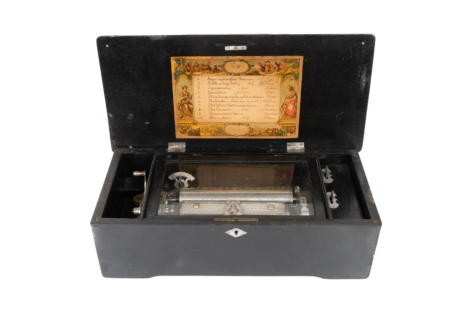 10 Tune Swiss Music Box: Swiss made music box, featuring glass-enclosed spring driven nickel mechanism with zither in wooden case, with case inscribed with tunes 5.5"h x 17.5"w x 8.5"d Condition: In working order,