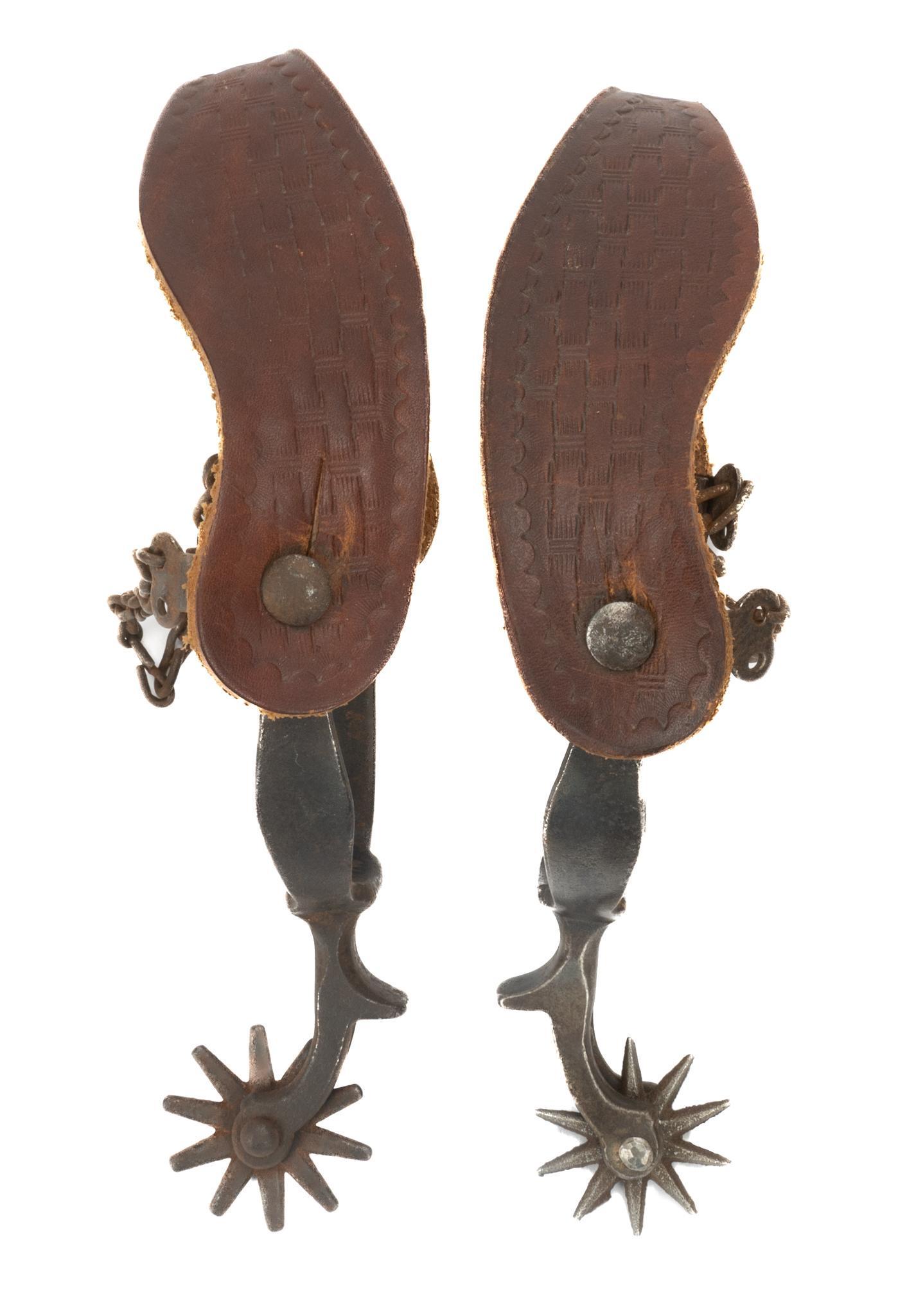 Pair of Cowboy Spurs, attrib. to August Buermann: Pair of cowboy spurs, attrib. to August Buermann, having embossed leather straps, iron bands, featuring scalloped motif 2"h x 6"w x 3.5"d Provenance: An Alamo Heights, Texas collection We happily