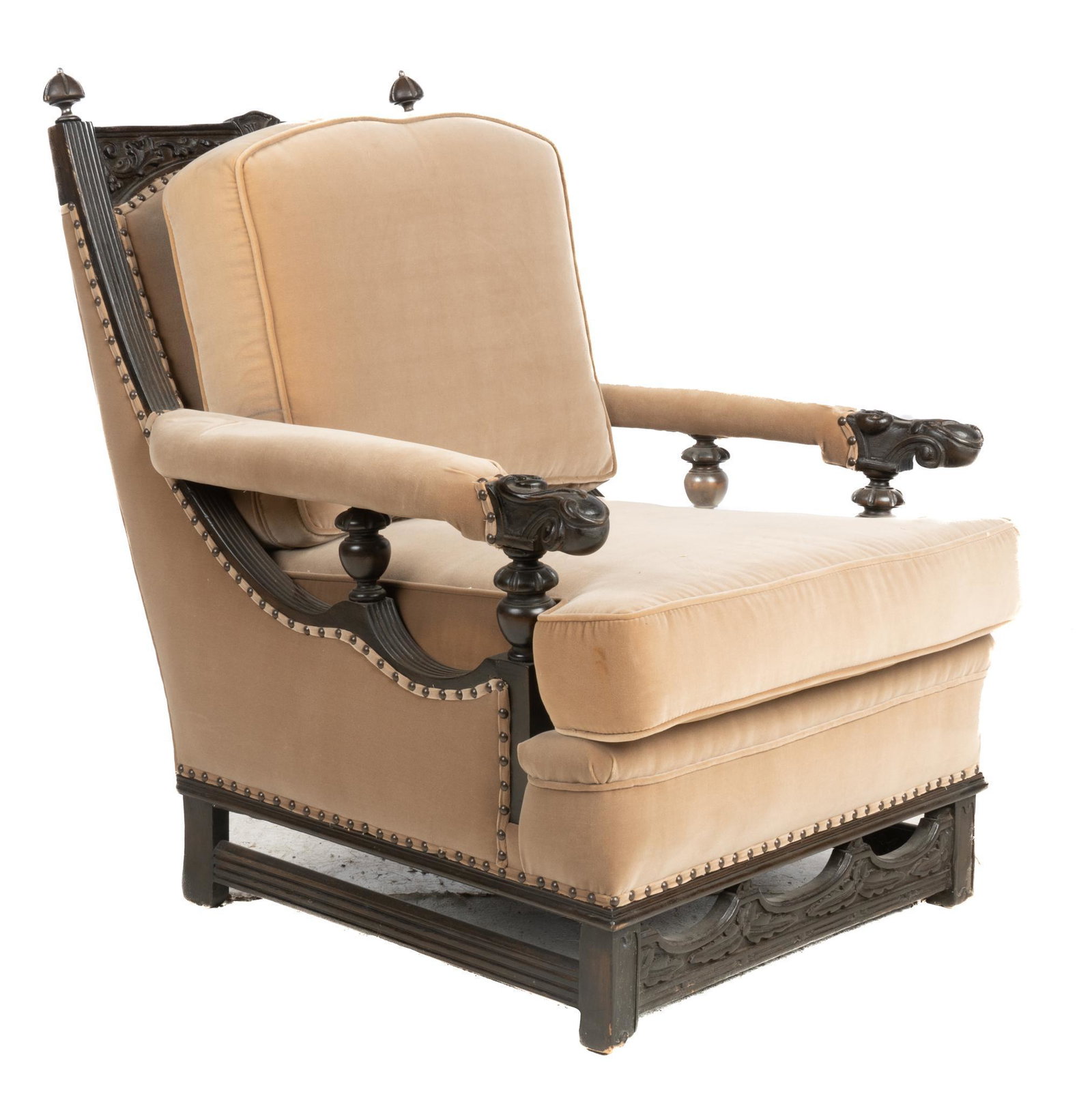 Carved Armchair: Upholstered armchair, having wooden frame, back and seat cushions, featuring carved finials, scroll motif, supported on stretchered block legs 39"h x 30"w x 39"d Provenance: A San Antonio, Texas colle