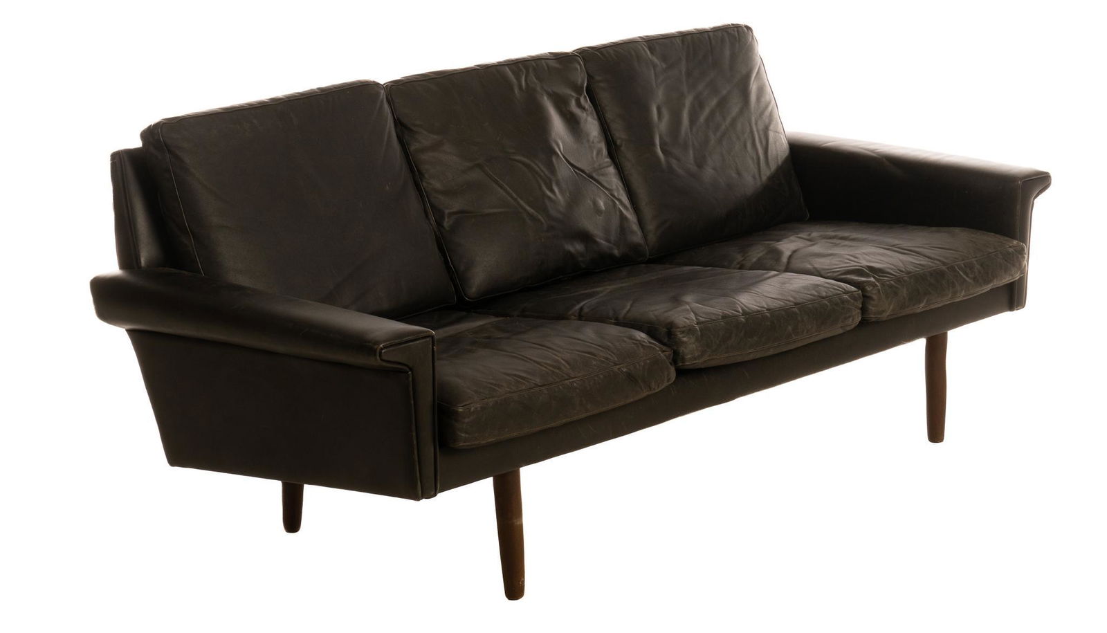 George Thams (20th C., DNK), Mid-Century Leather Sofa: Georg Thams (20th C., Denmark), Mid-Century three-seater sofa, featuring black leather upholstery, flared arms, rising on pin legs 28"h x 74"w x 27.5"d We happily provide seamless shipping services