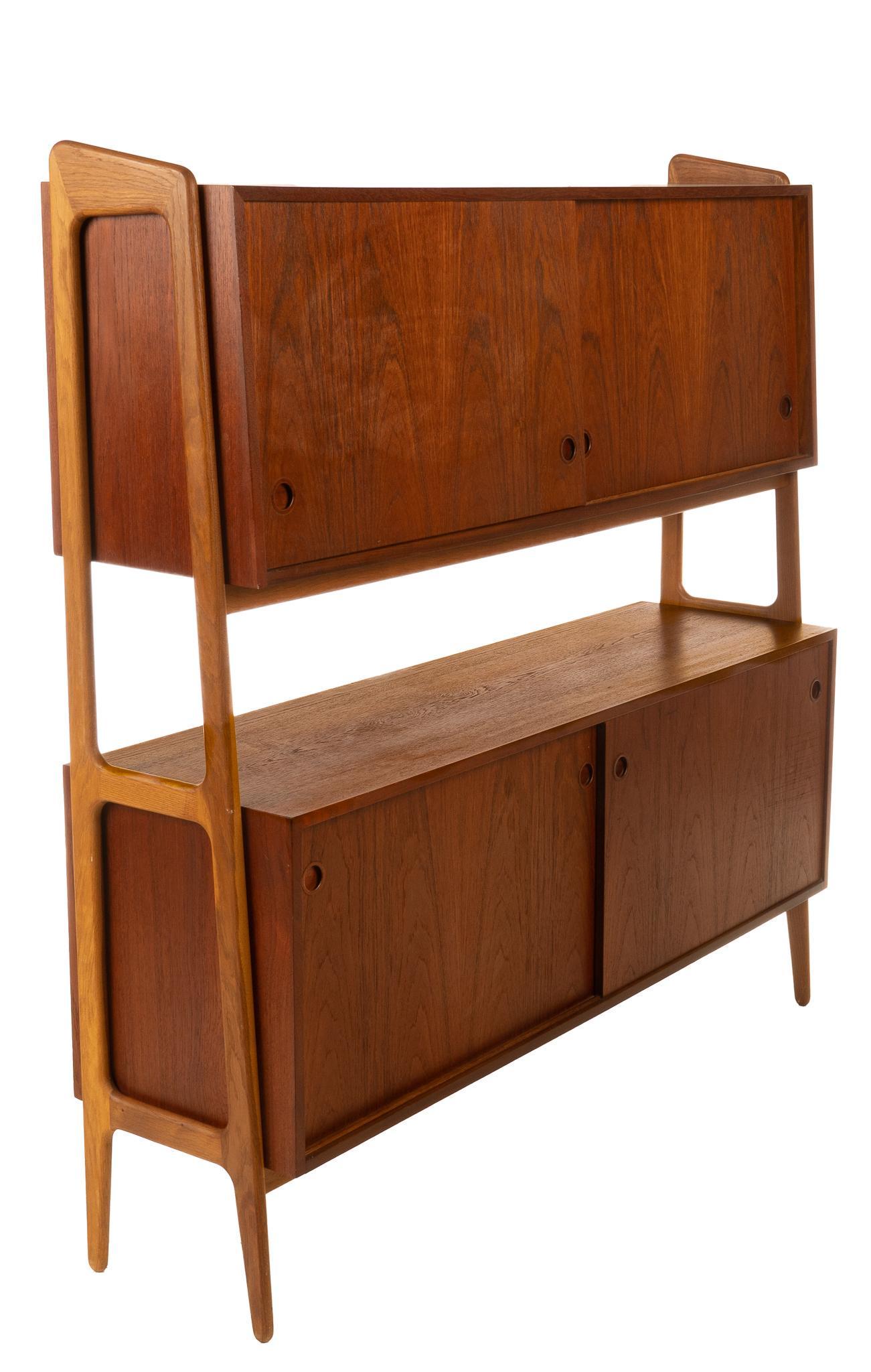 Danish Mid-Century Two-Tiered Buffet: Danish Mid-Century two-tiered buffet, having sliding doors, opening to interior shelving, supported on pin legs 60.5"h x 60.5"w x 17"d We happily provide seamless shipping services on everything we se