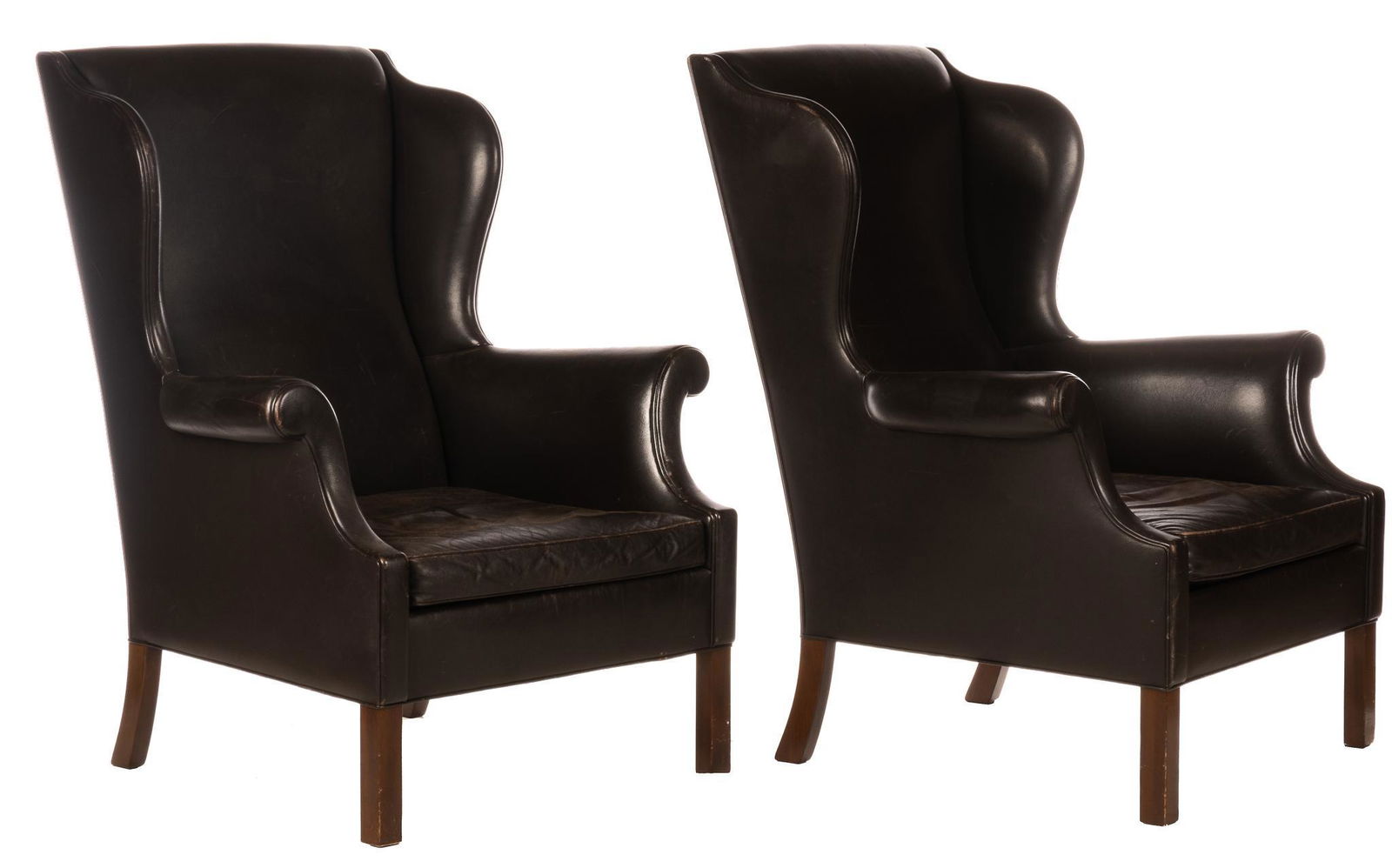 Pair of Leather Wingback Chairs: Pair of matching leather wingback chairs, featuring black leather upholstery, scrolled arms, rising on block legs 43"h x 25.5"w x 30"d We happily provide seamless shipping services on everything we