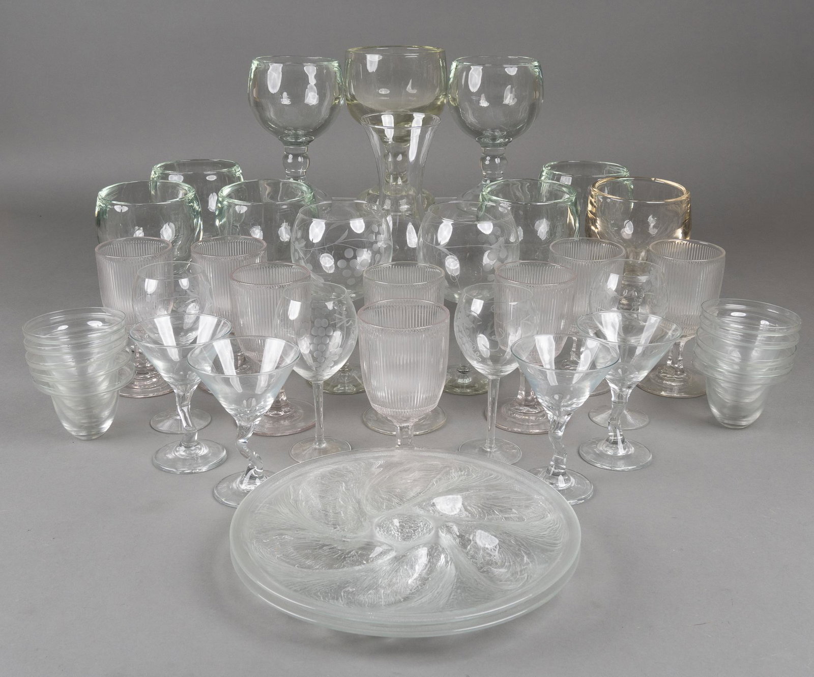 Collection of Glass Cocktail Glasses: Collection of glass cocktail glasses, to include wine glasses, martini glasses, etc., featuring mussel/oyster plate 11"h x 4"w x 4"d / tallest Provenance: The collection of Bill and Pat Cr
