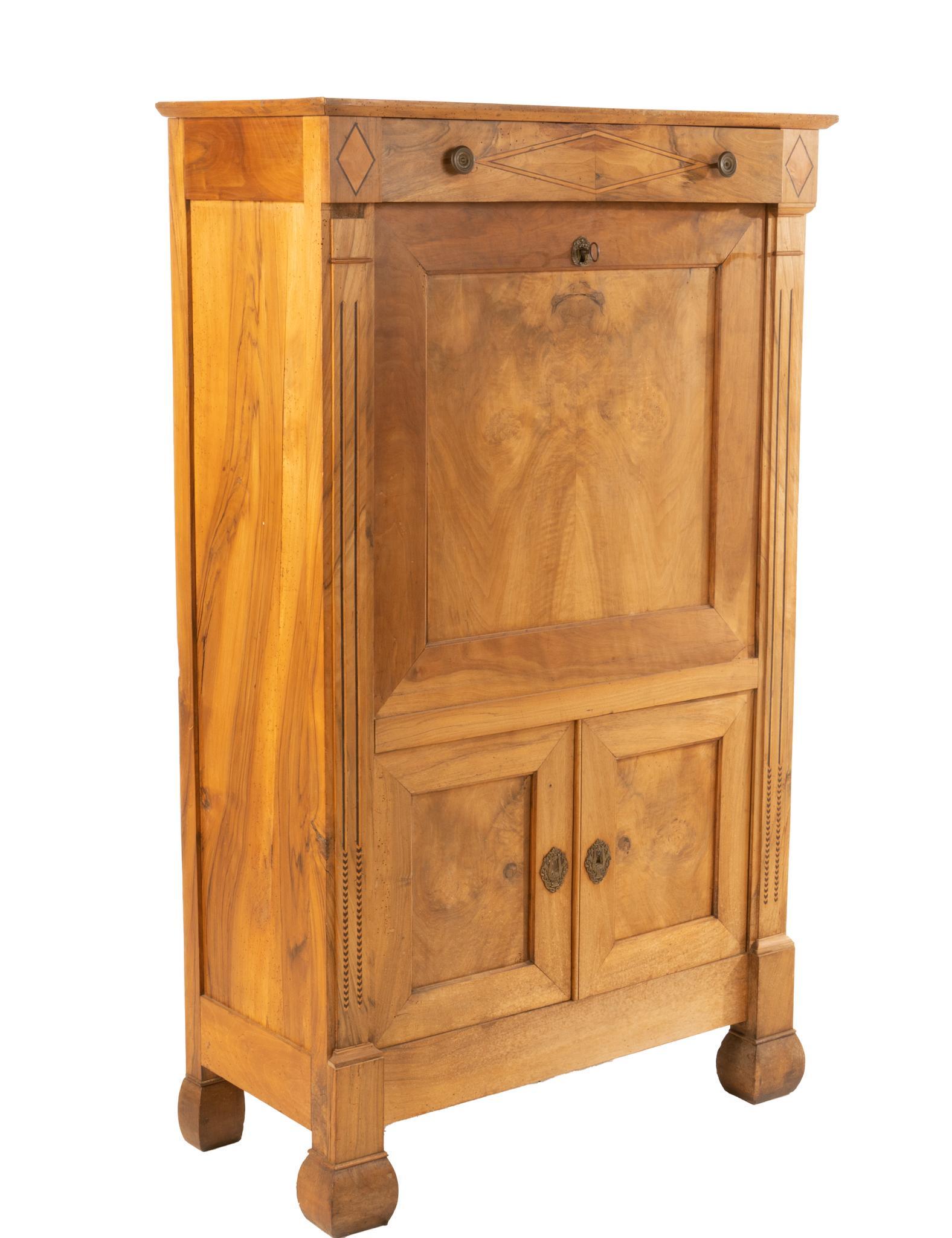 French Empire Style Secretary: French Empire style walnut secretary, having single drawer over drop down panel leading to interior compartments, additional cabinet storage, featuring carved accents, rising on bun feet, circa 1840