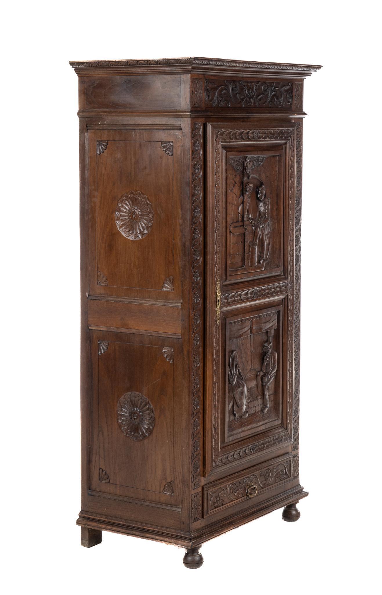 Renaissance Style Bonnetiere: Heavily carved Renaissance style bonnetiere, with cabinet door, featuring carved love story motif, opening to shelved interior, above drawer, supported on bun feet 63h x 31w x 19d We happily provide s