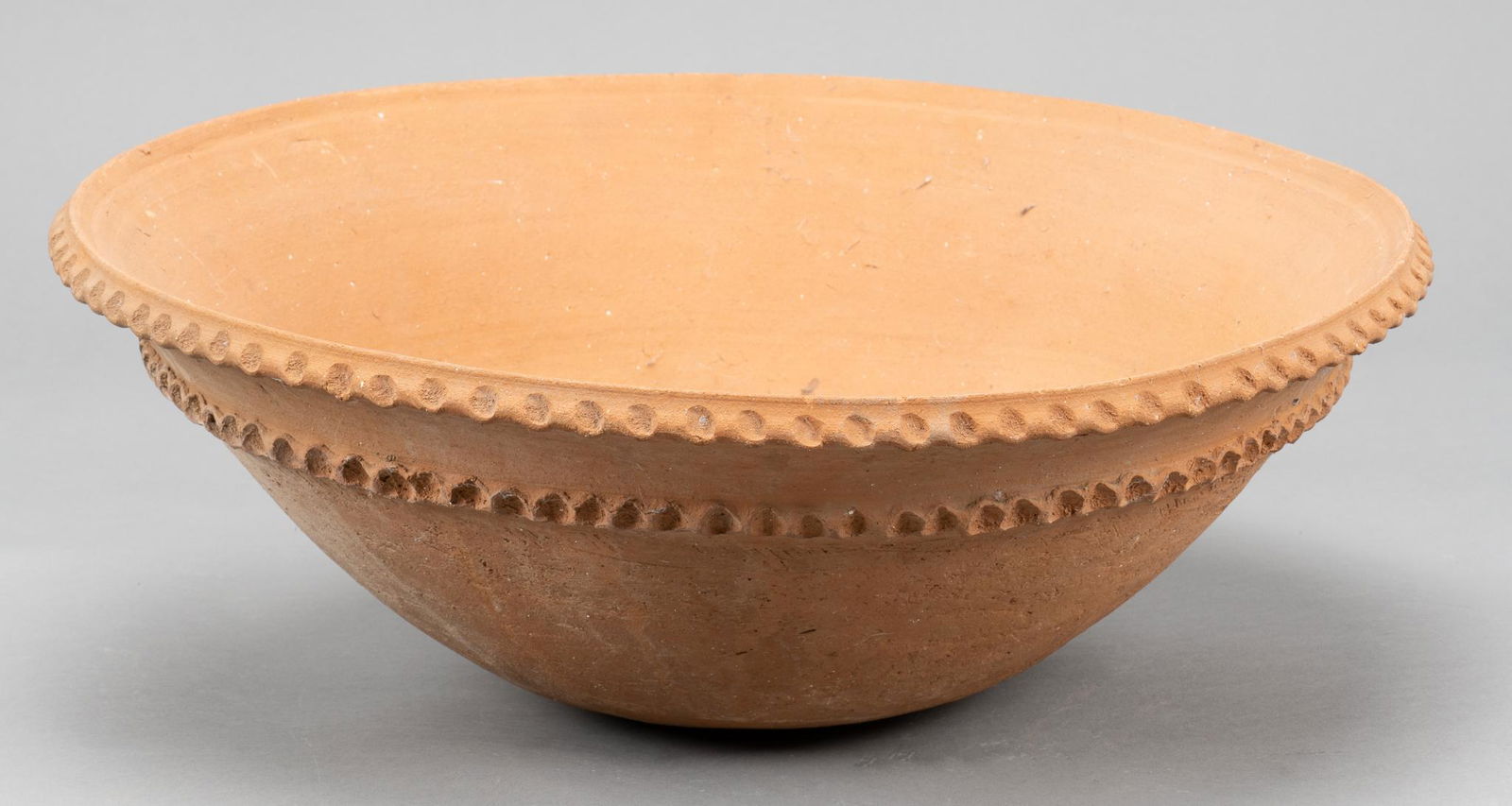 Mexican Orange Ware Bowl: Mexican (Tehuantepec, Oaxaca) orange ware bowl, wth ruffled banding, four perforated pin holes to interior base, marked "Tehuantepec / Oaxaca / Mexico" height 8 in. x diameter 22 in. Provenance: A