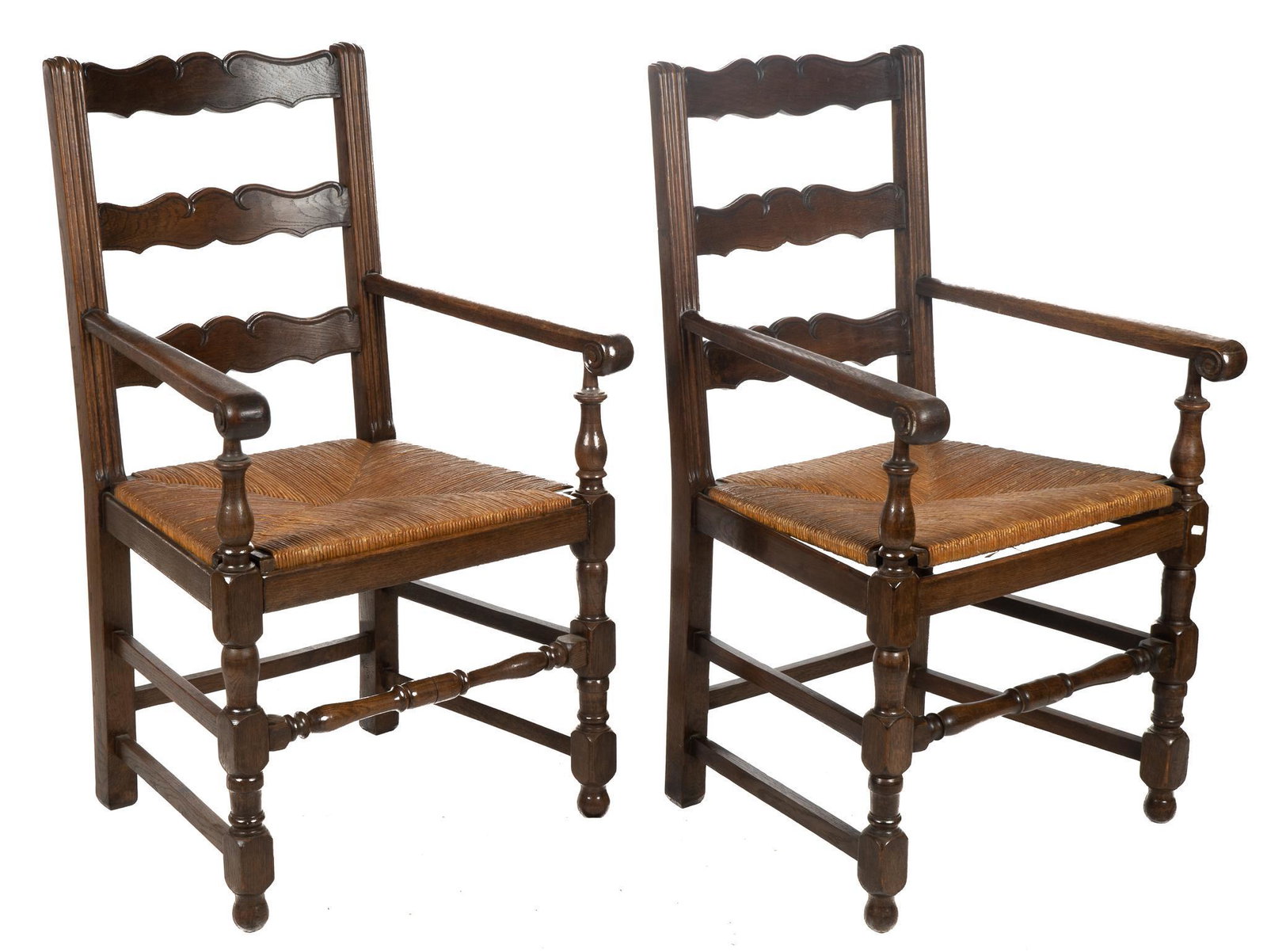 Pair of Rush Seat Armchairs: Pair of rush seat armchairs, having ladder backs, with carved scroll accents, scrolled armrests, supported on turned stretchered legs, ending in ball feet height 41.5 in. x width 24 in. x depth 25 in.