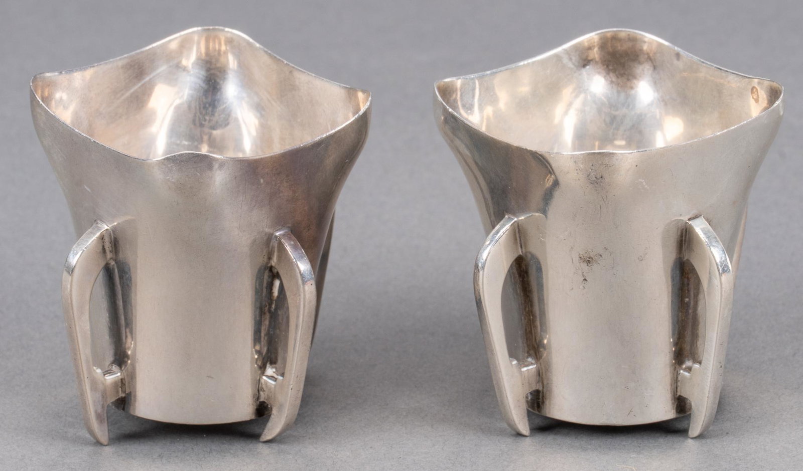 Antique English Secessionist Sterling Silver Wine Cups: Pair of Arts and Crafts sterling silver wine cups, one with England hallmarks, the other Ireland, circa 1906 Height 2 3/8 in.; total weight 5.25 ozt. Provenance: The Estate of Philip and Carolyn Moran