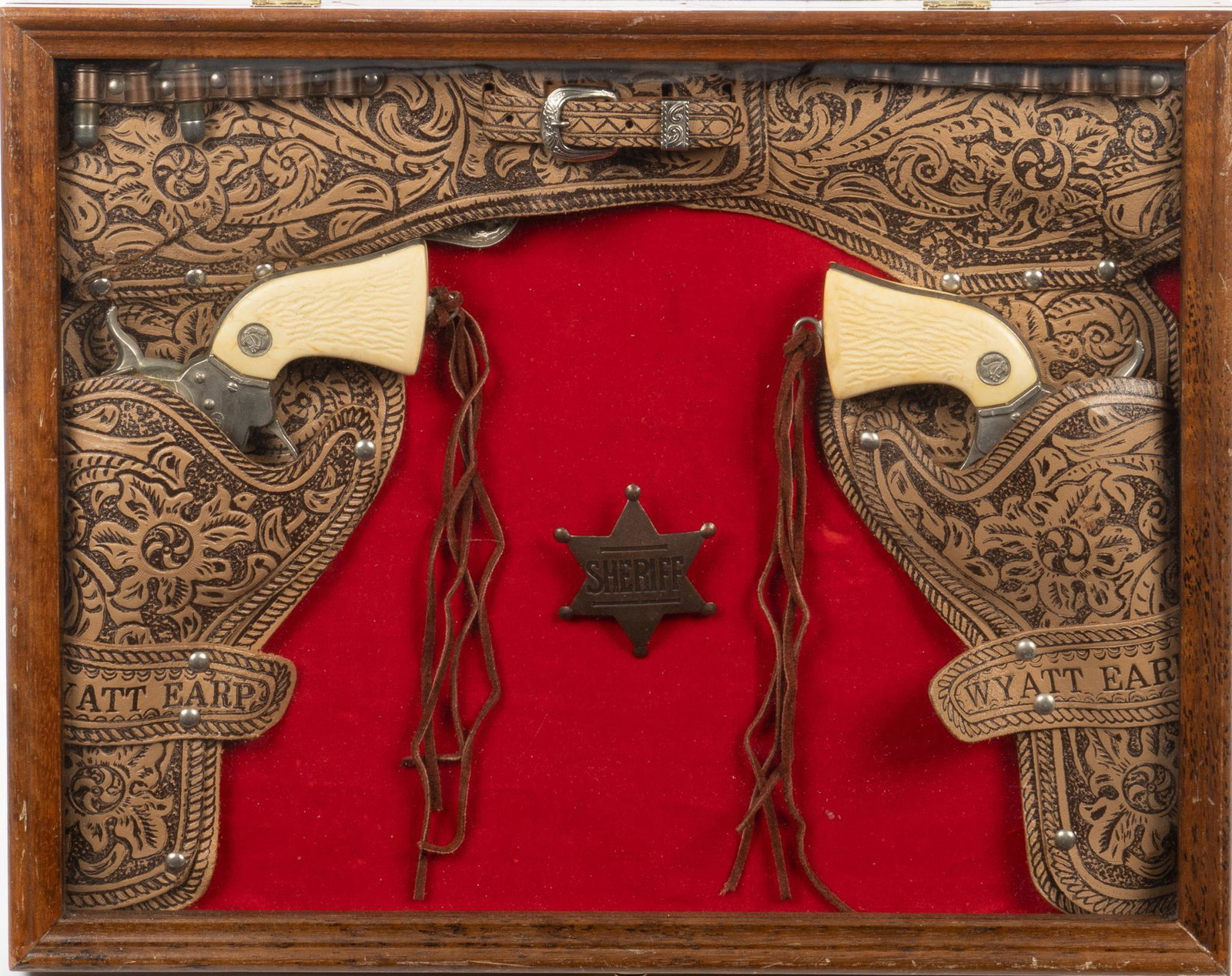 Framed Wyatt Earp Cap Gun Holster and Sheriff Badge: Wyatt Earp leather gun holster, with embossed floral decoration, marked "Wyatt Earp", holding cap gun, also to include sheriff's badge, framed height 13.5 in. x width 17 in. x depth 2 in. 