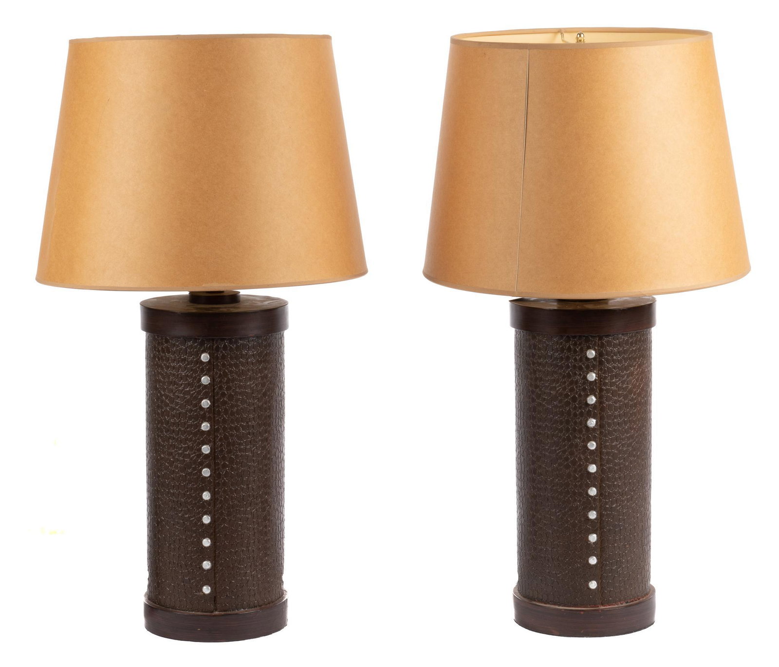 Pair of Leather Cook Lamps: Pair of Leather Cook lamps, having round bases, featuring band of carved leather motif, to include lampshade height 29 in. x width 16 in. x depth 16 in. We happily provide seamless shipping services o