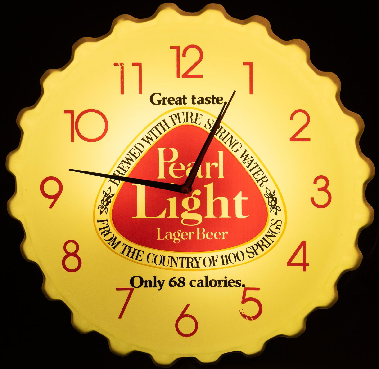 Pearl Light Bottle Cap Light Up Wall Clock: Pearl Light Lager Beer light up advertising wall clock, with crenelated bottle cap border, light-up acrylic face, Pearl Light logo at the center height 17 in. x width 17 in. x depth 2 in. €â�