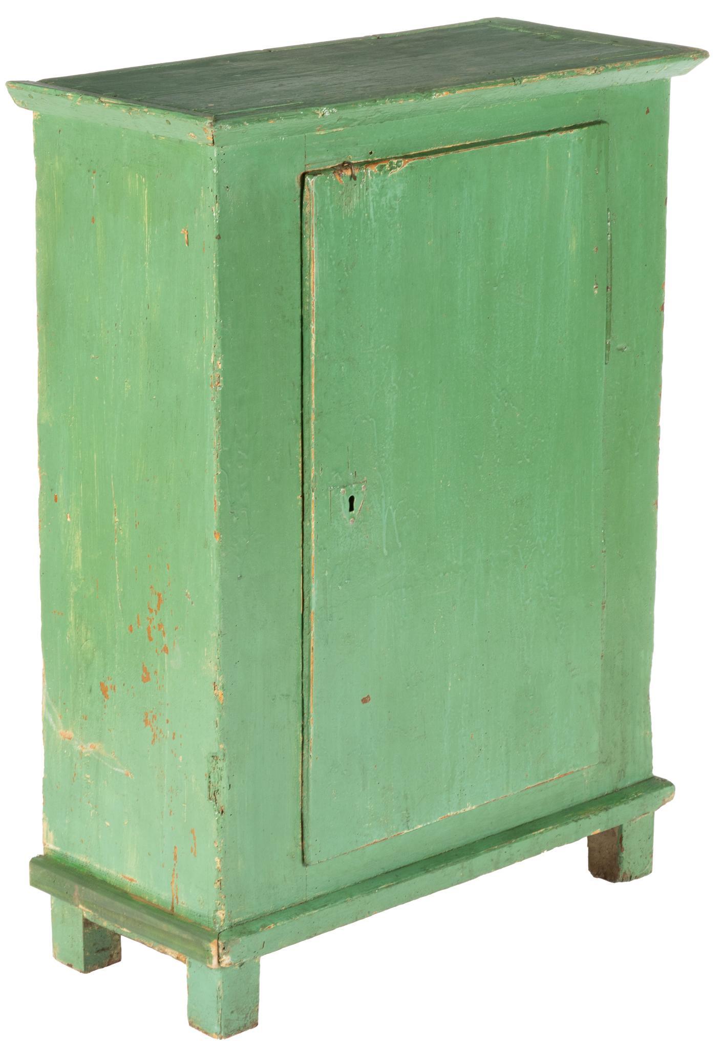 Painted Kitchen Cupboard: Kitchen cupboard, painted green, with an overhanging top over a single door opening to a two shelf interior, supported on block feet height 39 in. x width 29.5 in. x depth 13 in. We happily provide se