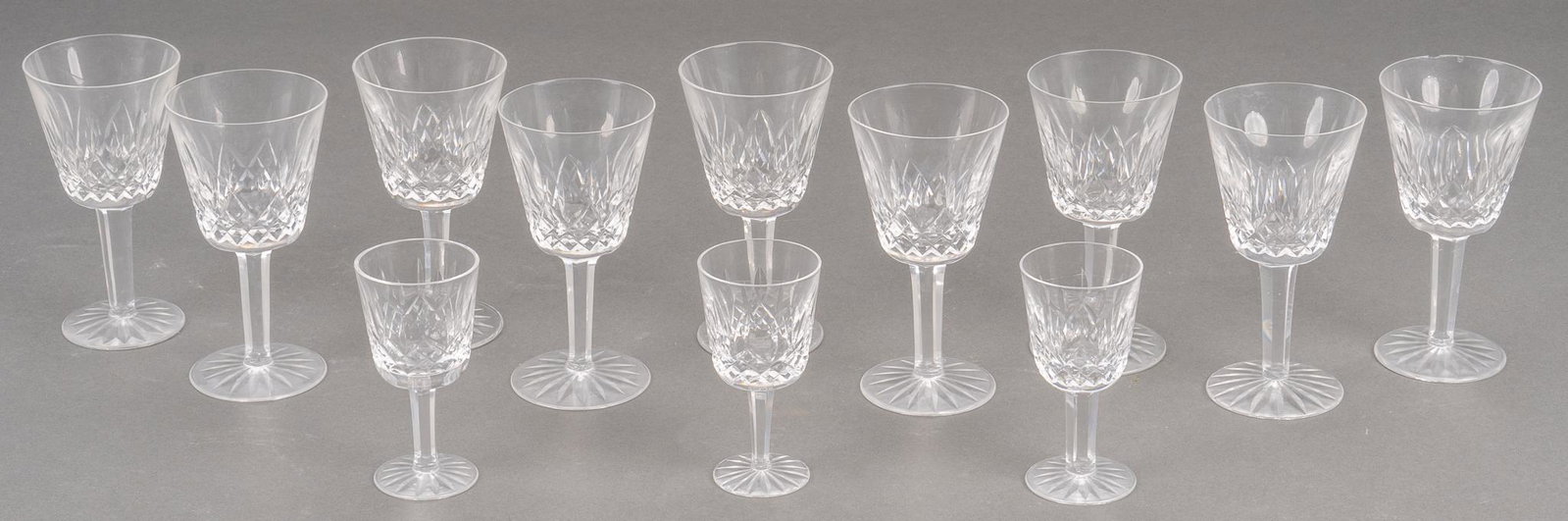 Waterford Crystal "Lismore" White Wine Glasses: Nine (9) white goblets in the "Lismore" pattern from Waterford Crystal; also includes three "Lismore" cordials. Goblets height 5 3/4 in., cordials 4 1/4 in. Provenance: The Estate of C