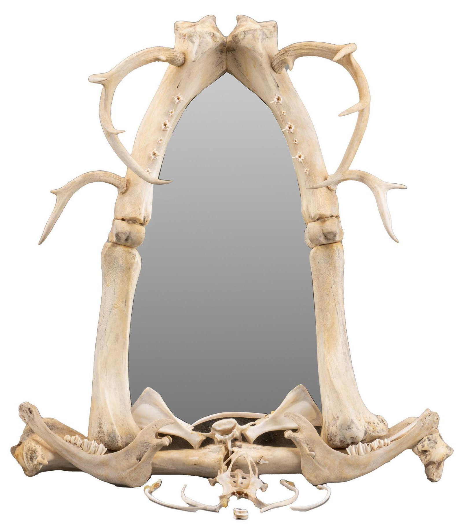 Bone and Antler Taxidermy Wall Mirror: Bone and antler taxidermy wall mirror, with shield shaped mirror face, supported in near-symmetrical frame made from assembled bone fragments, includes antler, jaw bones, four extra bone pieces, suppo
