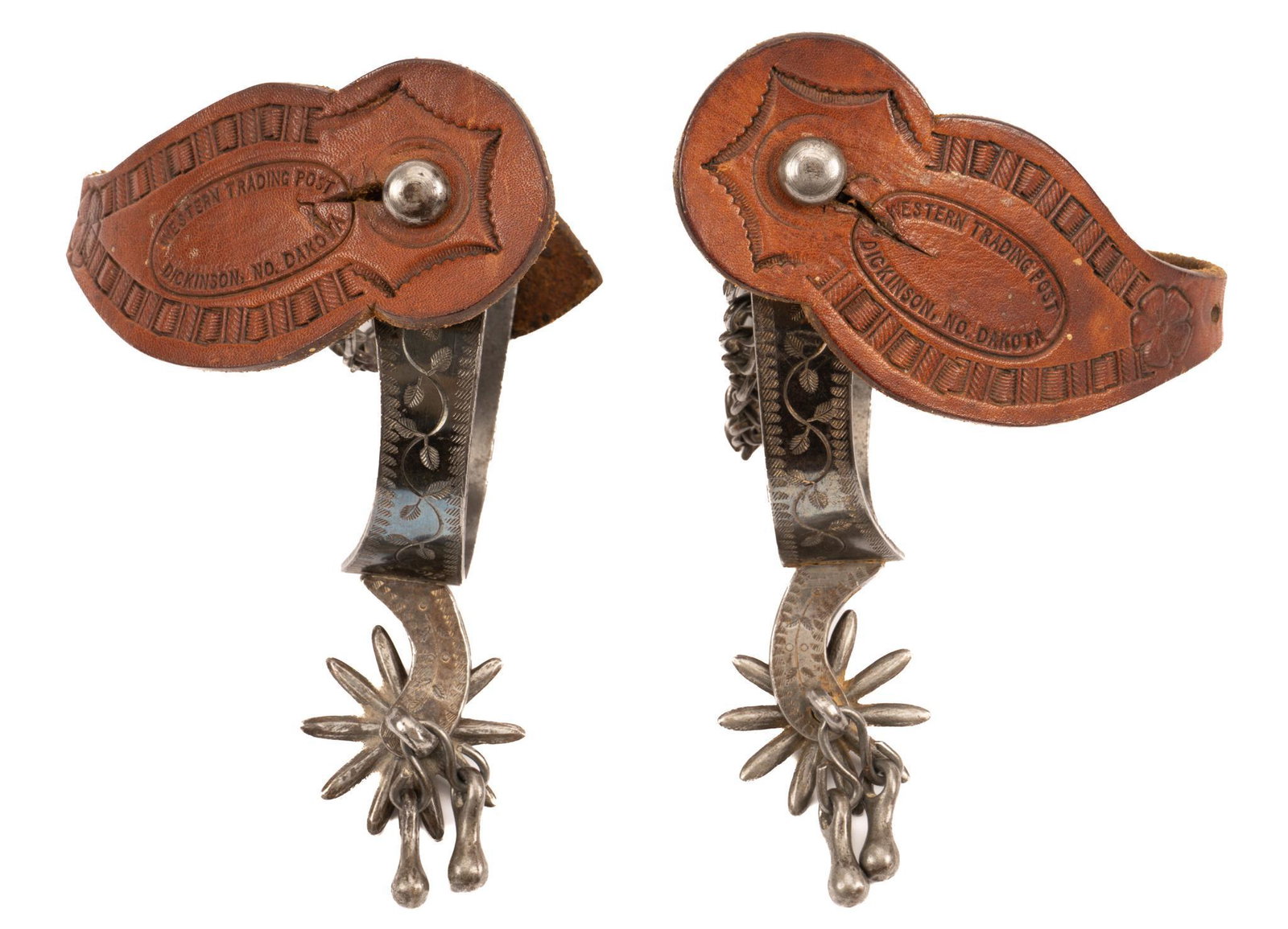 19th/20th C. "Patent" Marked Spurs: Pair of "patent" marked spurs, with steel heel bands, engraved vine motifs, ten point rowels with jingle bobs, spur chains, leather heel straps marked "Western Trading Post / Dickinson, NO