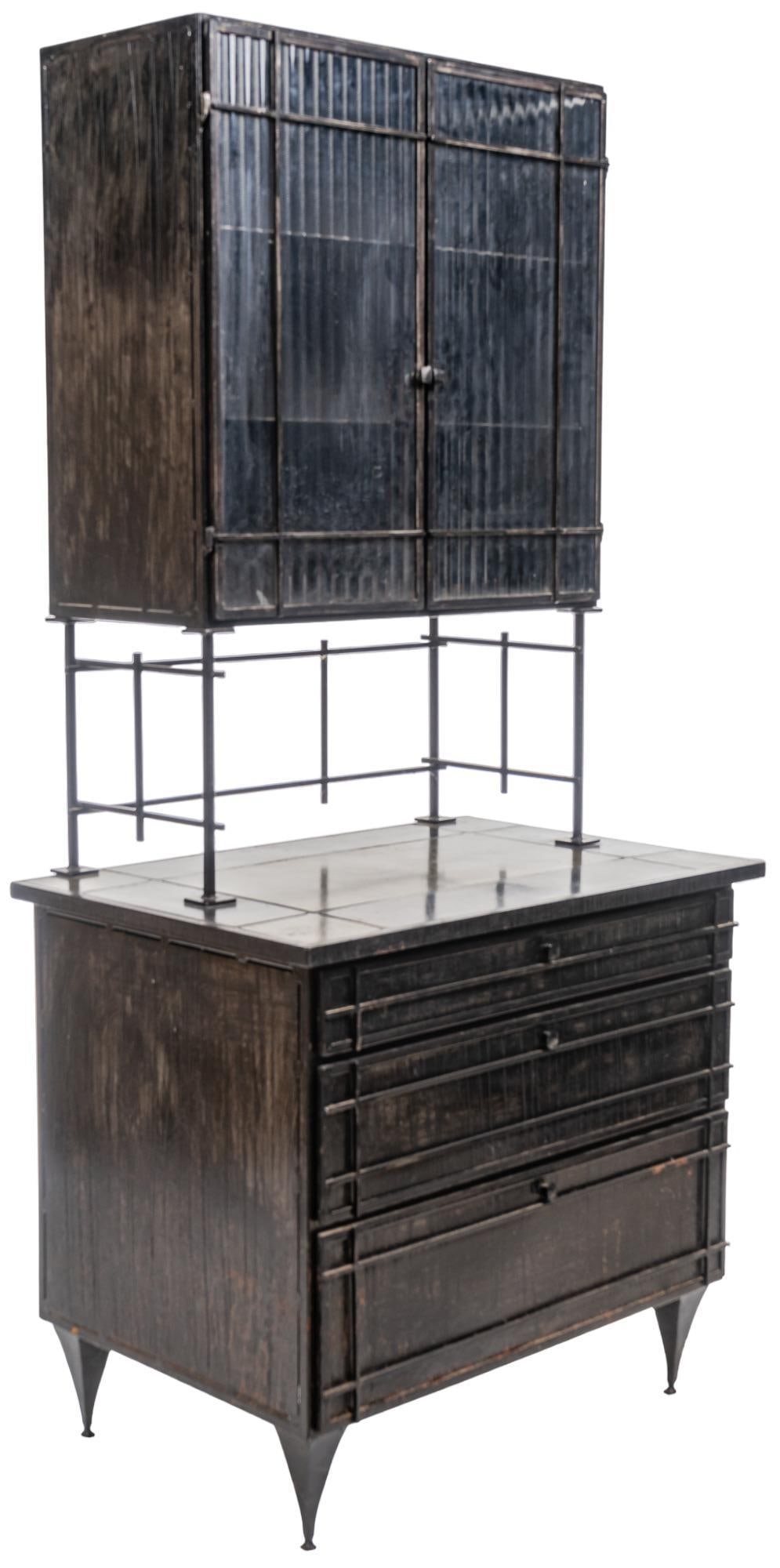 Glass and Metal Credenza: Two level metal credenza, featuring top section with double doors with ribbed glass, opening to reveal shelved interior, rising on stretchered metal stand, resting on lower storage unit, which feature