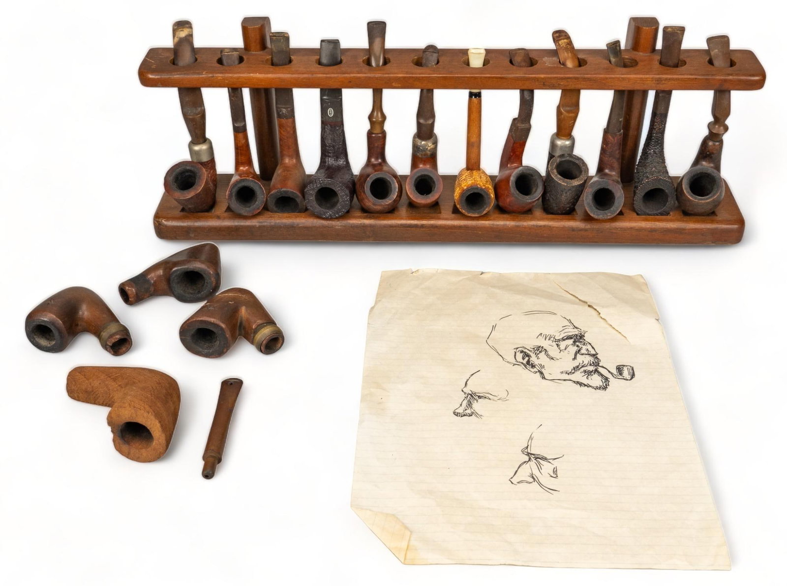 Collection of (12) Smoking Pipes: Bill Wittliff's collection of twelve smoking pipes, with wooden storage rack, also includes four smoking pipe bowls hand-carved by Wittliff, along with a single sheet of notebook paper, featuring sket