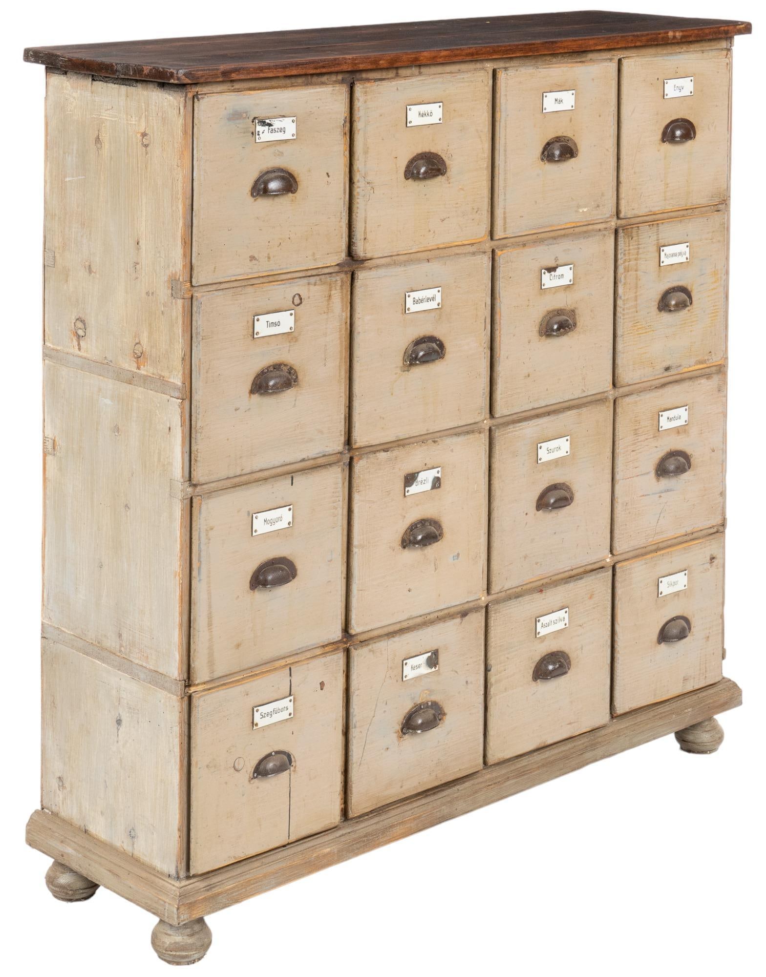 General Store Apothecary Cabinet: General store apothecary cabinet / bank of sixteen drawers, each having label and metal pull, wooden top, raised on bun feet, painted height 47 in. x width 43.5 in. x depth 13.5 in. We happily provide