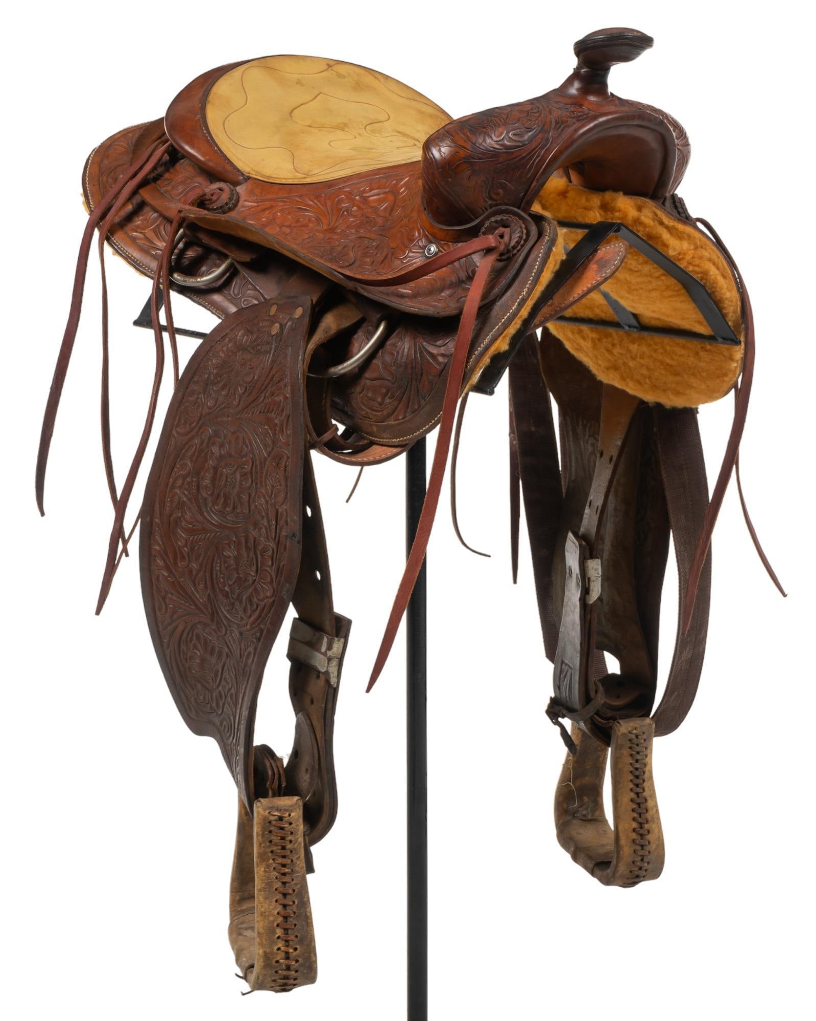 Western Tooled Leather Cowboy Saddle: Western cowboy saddle, tooled leather, metal accents, leather pommel height 36 in. x width 19 in. x depth 24 in. Provenance: Property from a San Antonio, Texas collection We happily provide seamless s