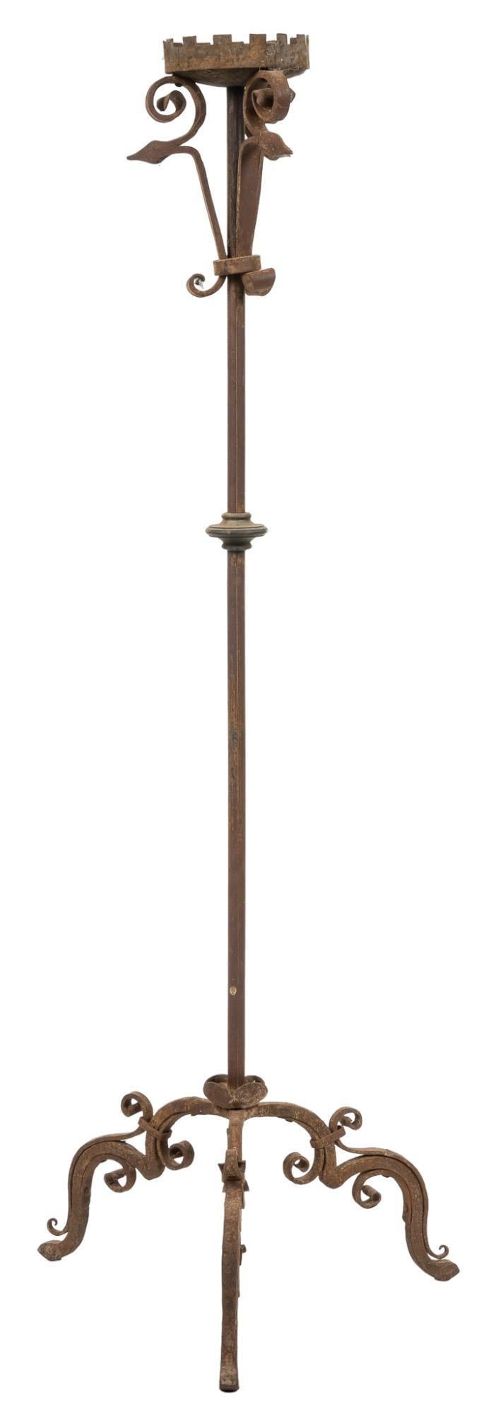 Wrought Iron Floor Candelabra: Wrought iron floor candelabra, supporting single candle, featuring zoomorphic motifs, on scrolled legs height 63 in. x diameter 21 in. Provenance: Property from the estate of long-time antiques dea