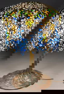 Signed Tiffany Studios Wisteria Table Lamp: Stained glass table lamp, featuring leaded stained glass blue wisteria shade, with bronze branches, irregular lower border, inside brass plate impressed "Tiffany Studios New York", "27770-D", supporte