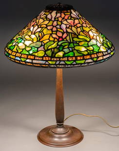 Signed Tiffany Stained Glass Botanical Table Lamp: Stained glass table lamp, with stained slag glass cone shade, marked Tiffany Studios New York, with three bulb paddle sockets, marked Bryant, supported on bronze architectural base, with areas of natu