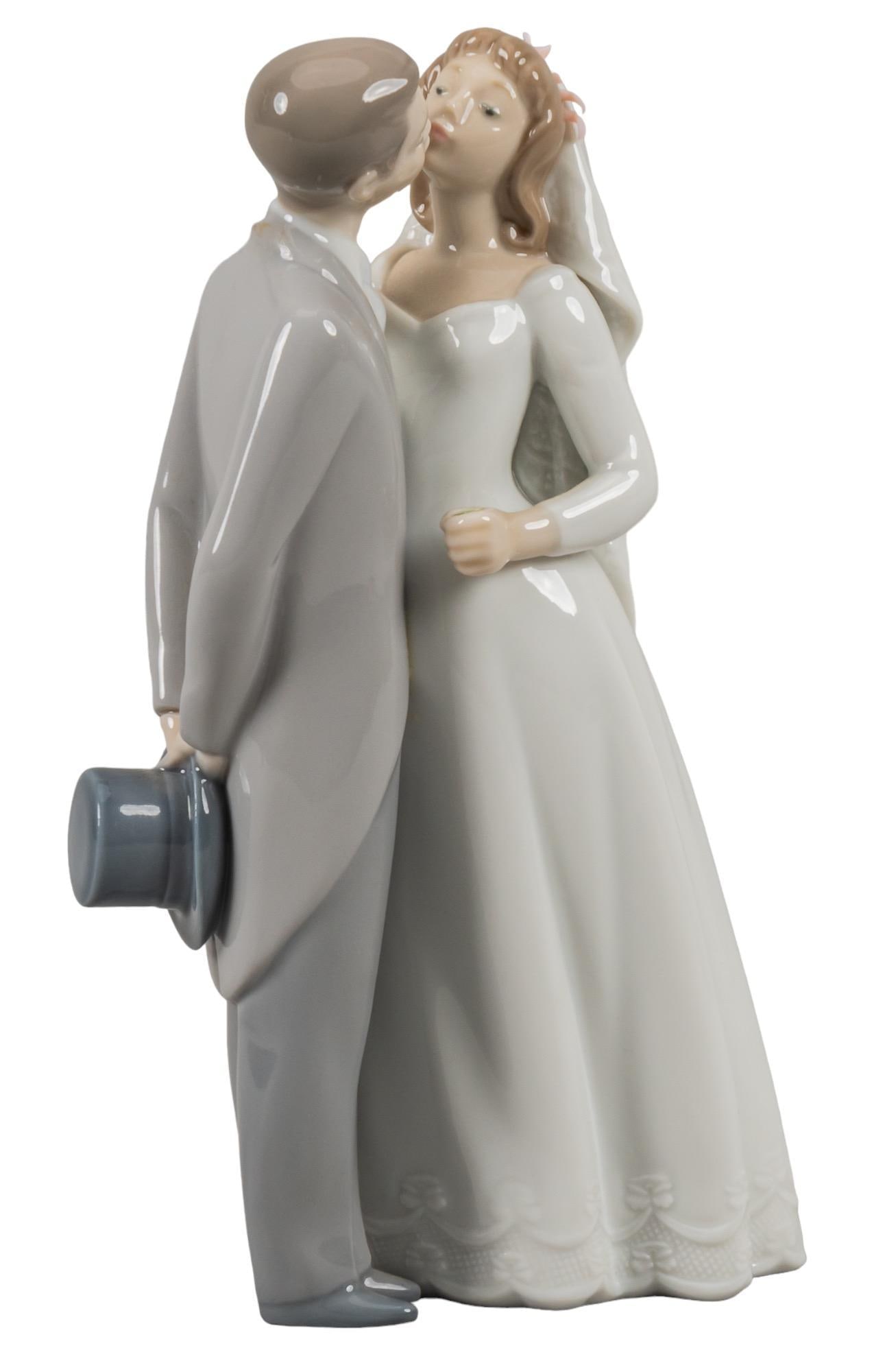 Lladro "A Kiss to Remember" Porcelain Figurine: Lladro "A Kiss to Remember" glossy porcelain figurine of a kiss from bride and groom, with a small bouquet of flowers and floral ornaments applique, model 6620, marked with maker and serial nu