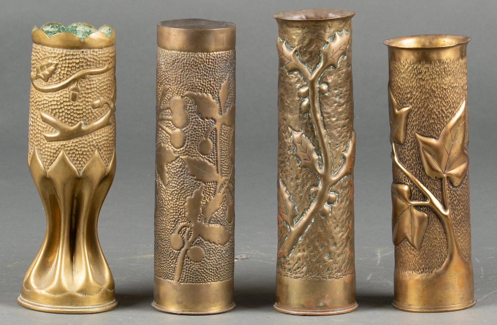 Set of 4 Oak and Leaf Engraved WWI Trench Art Vases: Includes: 3- French 75mm casings, one featuring Ivy, one Holly branch, one unknown branch 1- British 18 Pounder Casing, featuring an Oak branch Longest: 12 in. Shipping available for this lot through 